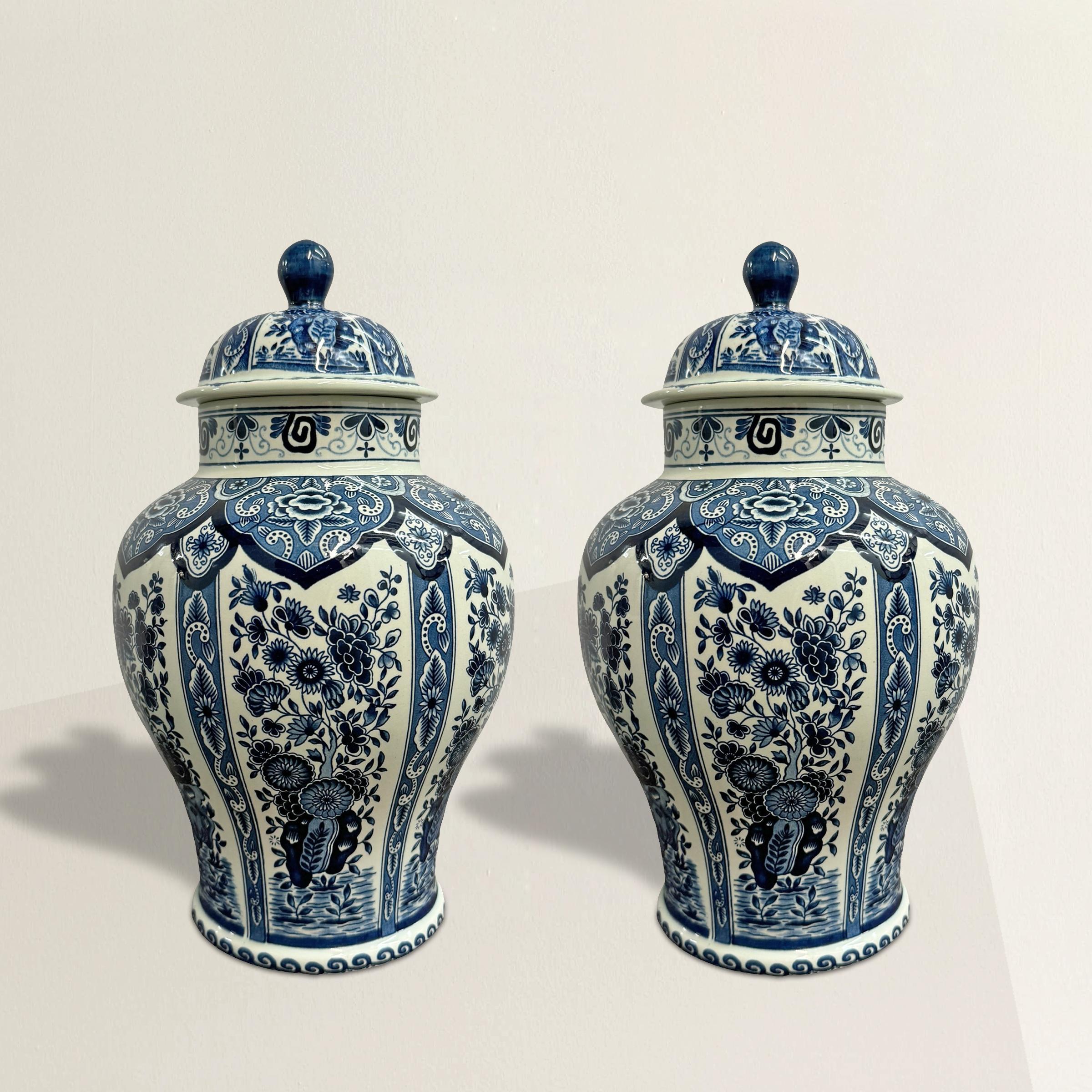 This exquisite pair of mid-20th century Dutch Delft ginger jars showcases the enduring beauty of blue and white pottery. Each jar features wide, graceful shoulders tapering into narrow waists, creating a classic and elegant silhouette. The surface