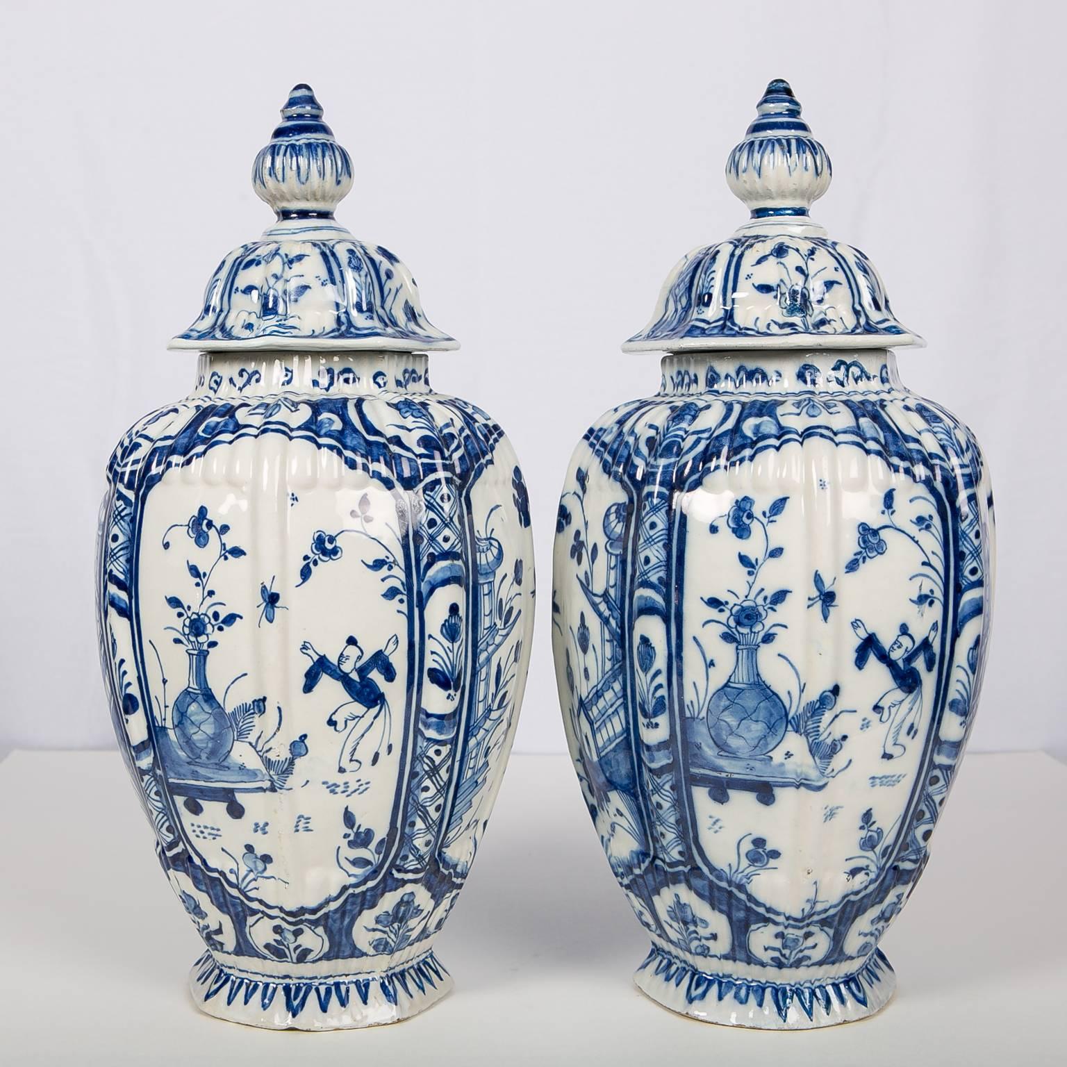 A pair of octagonal Dutch delft covered jars painted in a beautiful shade of cobalt blue. Made in the 18th century, circa 1770, the jars have hand-painted panels with delicate chinoiserie decoration. The covers are topped by traditional lotus bud