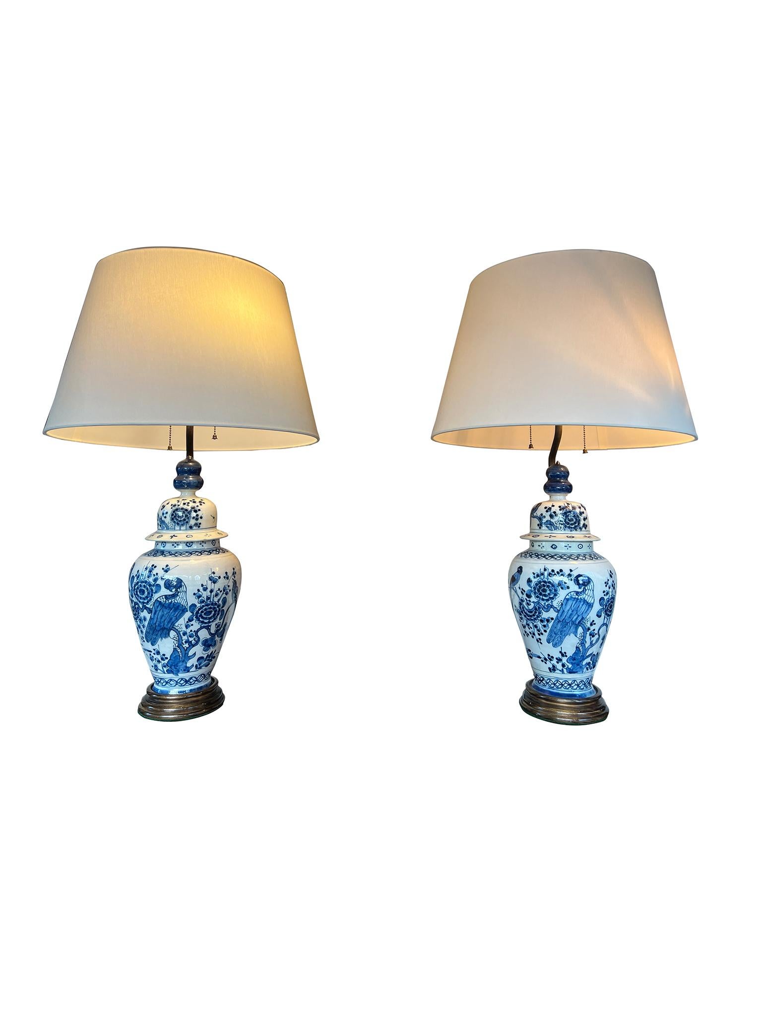 Charmantes Paar Delfter Porzellan-Tischlampen im Stil chinesischer Ingwer- oder Urnenlampen mit Deckel. Die Lampen sind mit dem Bild eines auf einem Baum sitzenden Vogels verziert, der von floralen Elementen umgeben ist. Die Lampen sind mit neuen