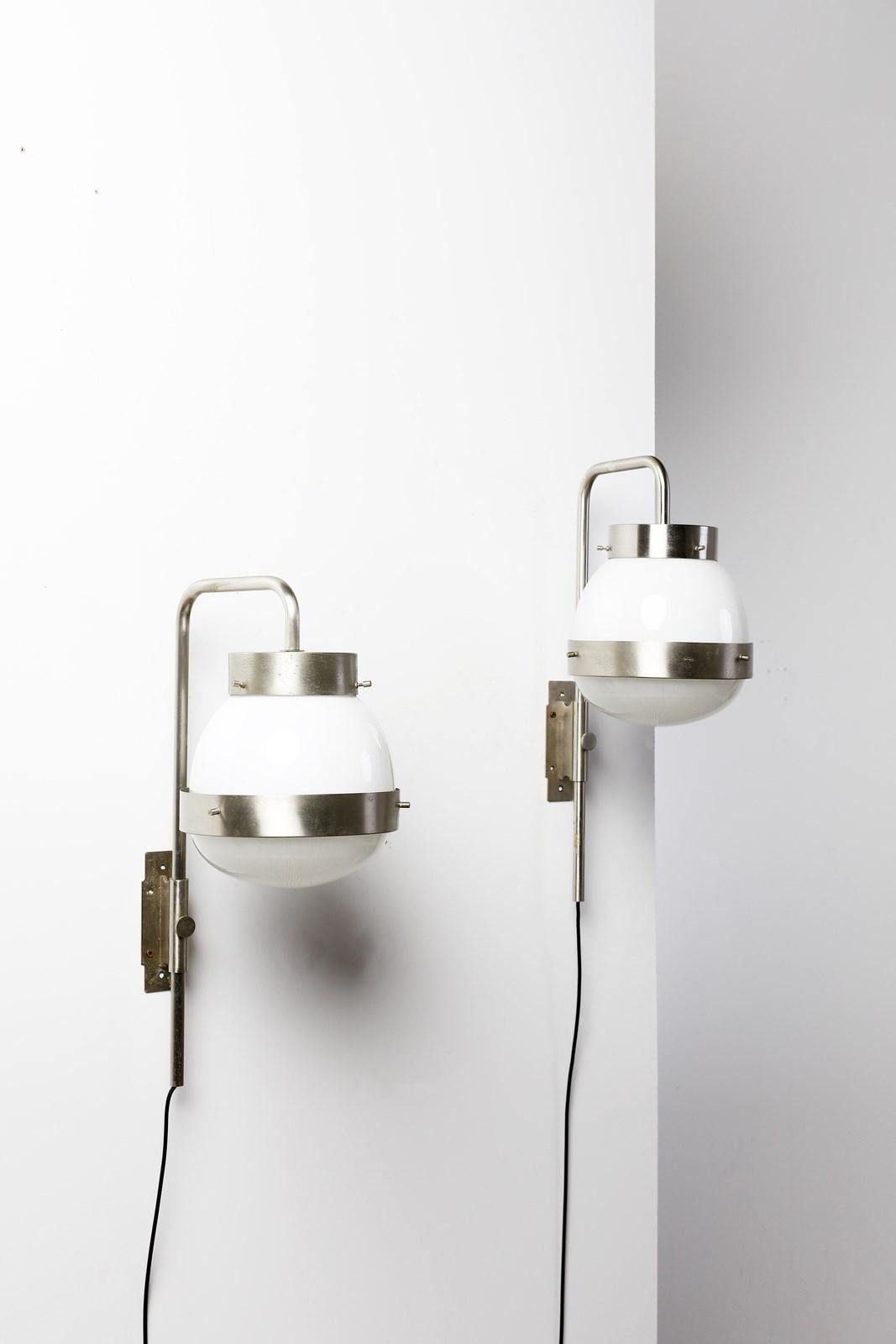 A sophisticated set of two 'Delta' wall lamps crafted by designer Sergio Mazza for Artemide in the 1960s. These adjustable lamps feature a satin steel frame, opal glass diffuser, and a meticulously molded crystal cup. This 'Delta' model offers a