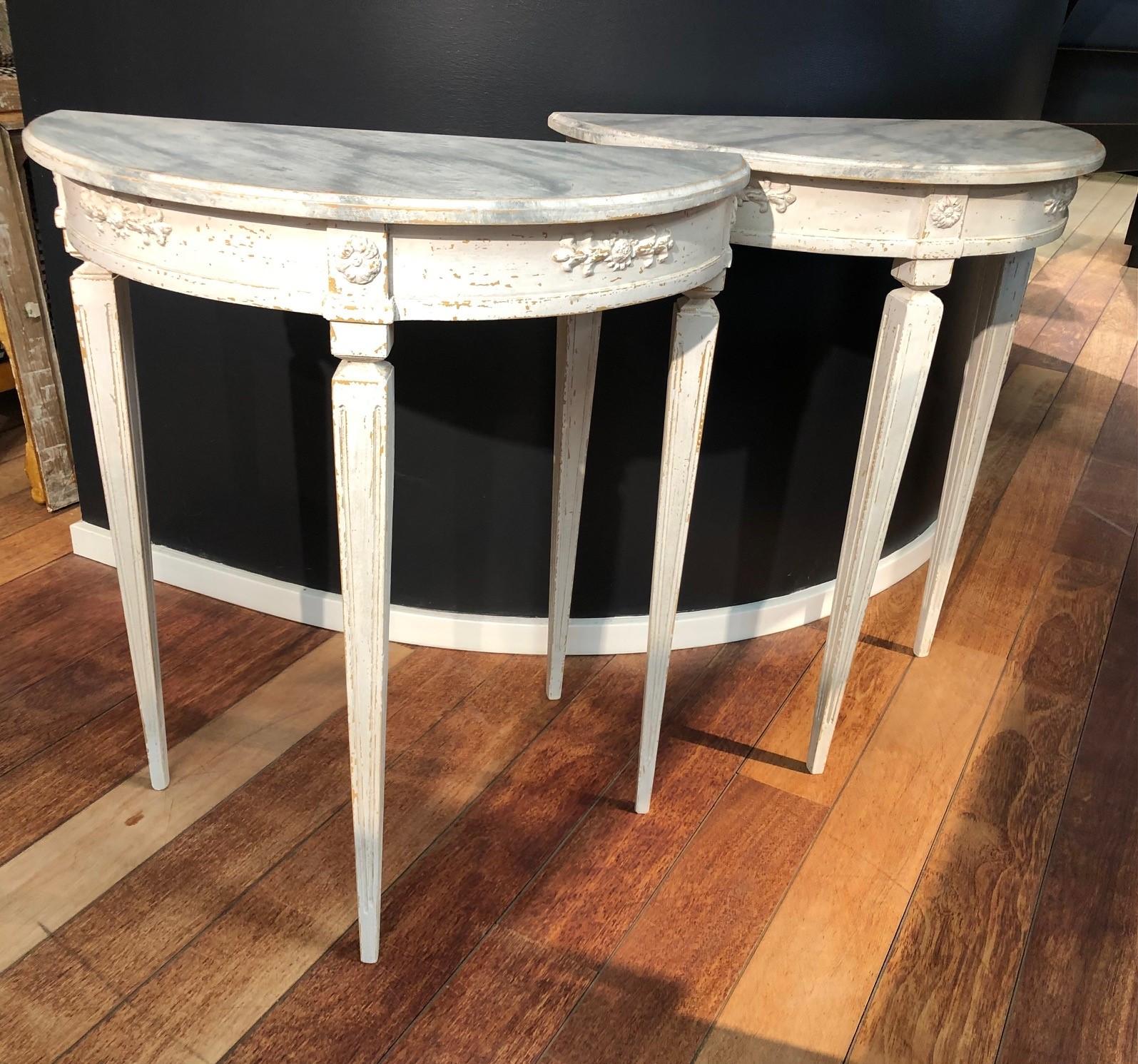 Elegant pair of demi lune console tables in Gustavian style.
Gray marbled table top with edge profile, frame with flower and foliage ornamentation.
Lower part blue painted, tapered legs with flutes.
Sweden approx. 1900.