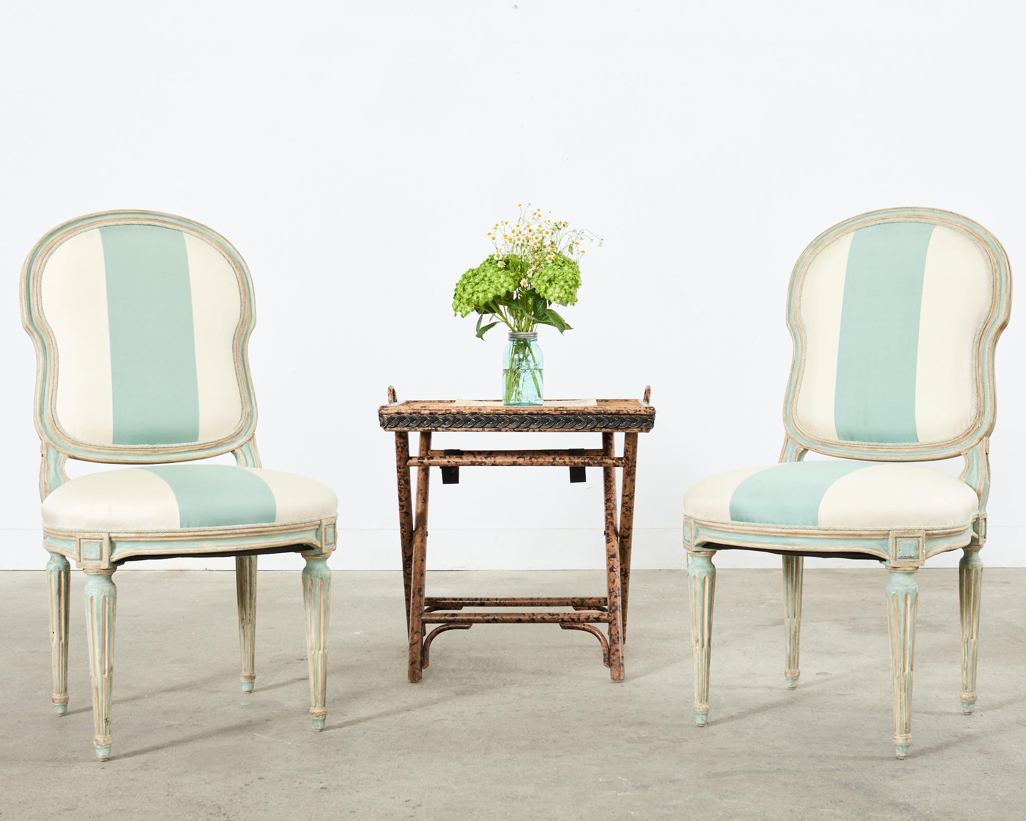 Gorgeous pair of distressed dining chairs made in the neoclassical French Louis XVI taste by Dennis & Leen Hollywood, CA. The Louis XVI side chairs feature an intentionally aged painted patina in a robin's egg green or verdigris as Dennis & Leen