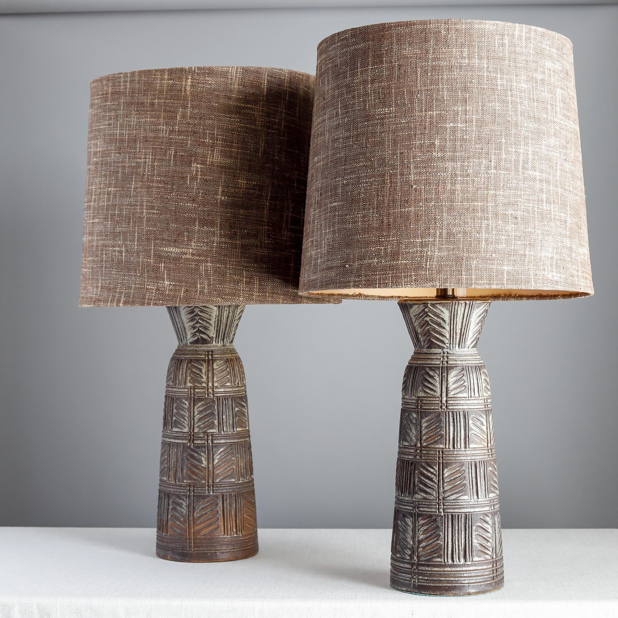 Pair of large ceramic lamps designed by Lee Rosen for Design Technics of Stroudsburg, PA. Each base has a distinctive carved design and dates to the 1950s. Includes original milk glass shades and brown fabric-covered paper shades. Original wiring.