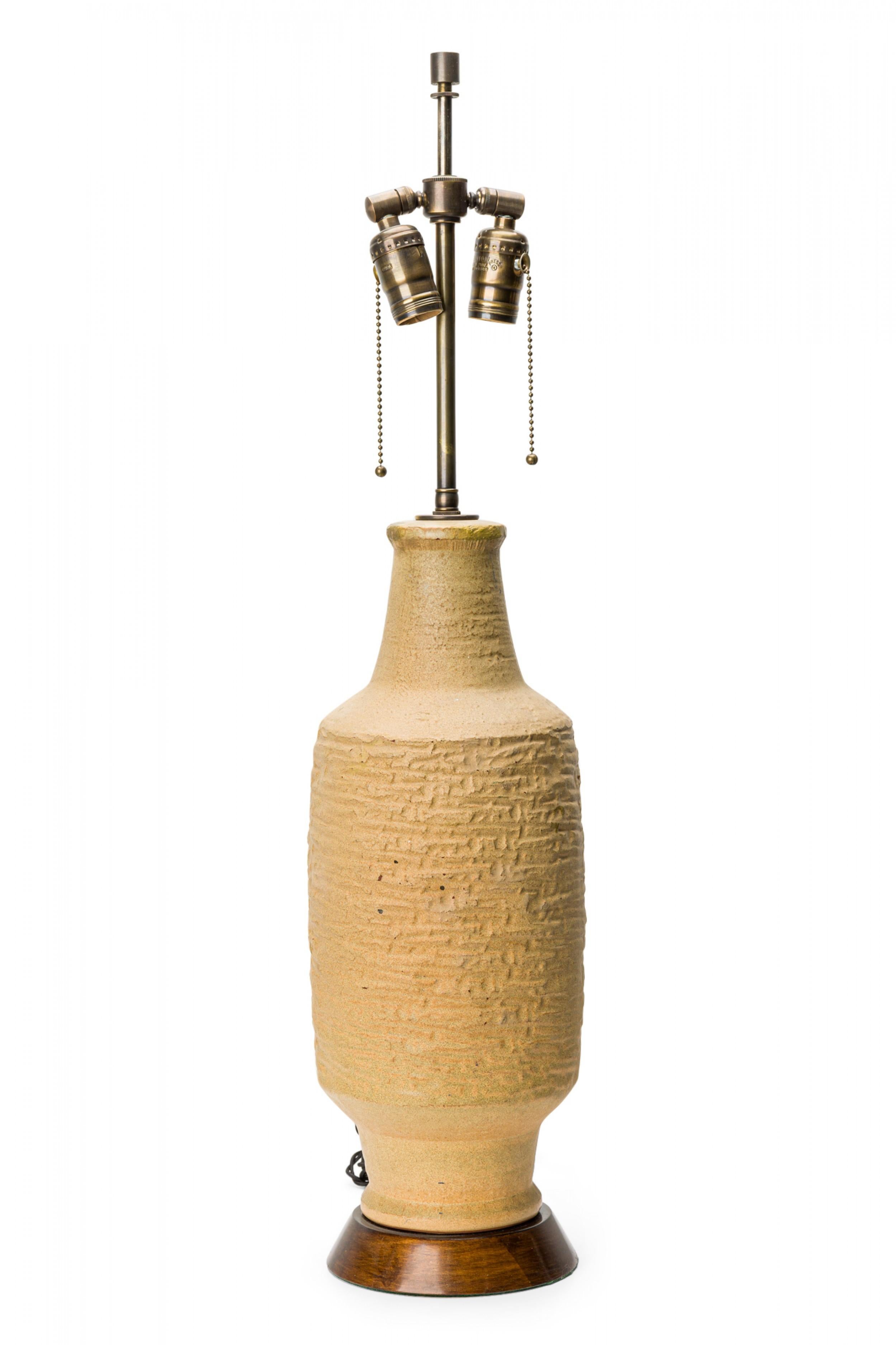 PAIR of Mid-Century cylindrical table lamps with textured beige ceramic forms resting on a round wood base. (DESIGN TECHNICS)(PRICED AS PAIR).