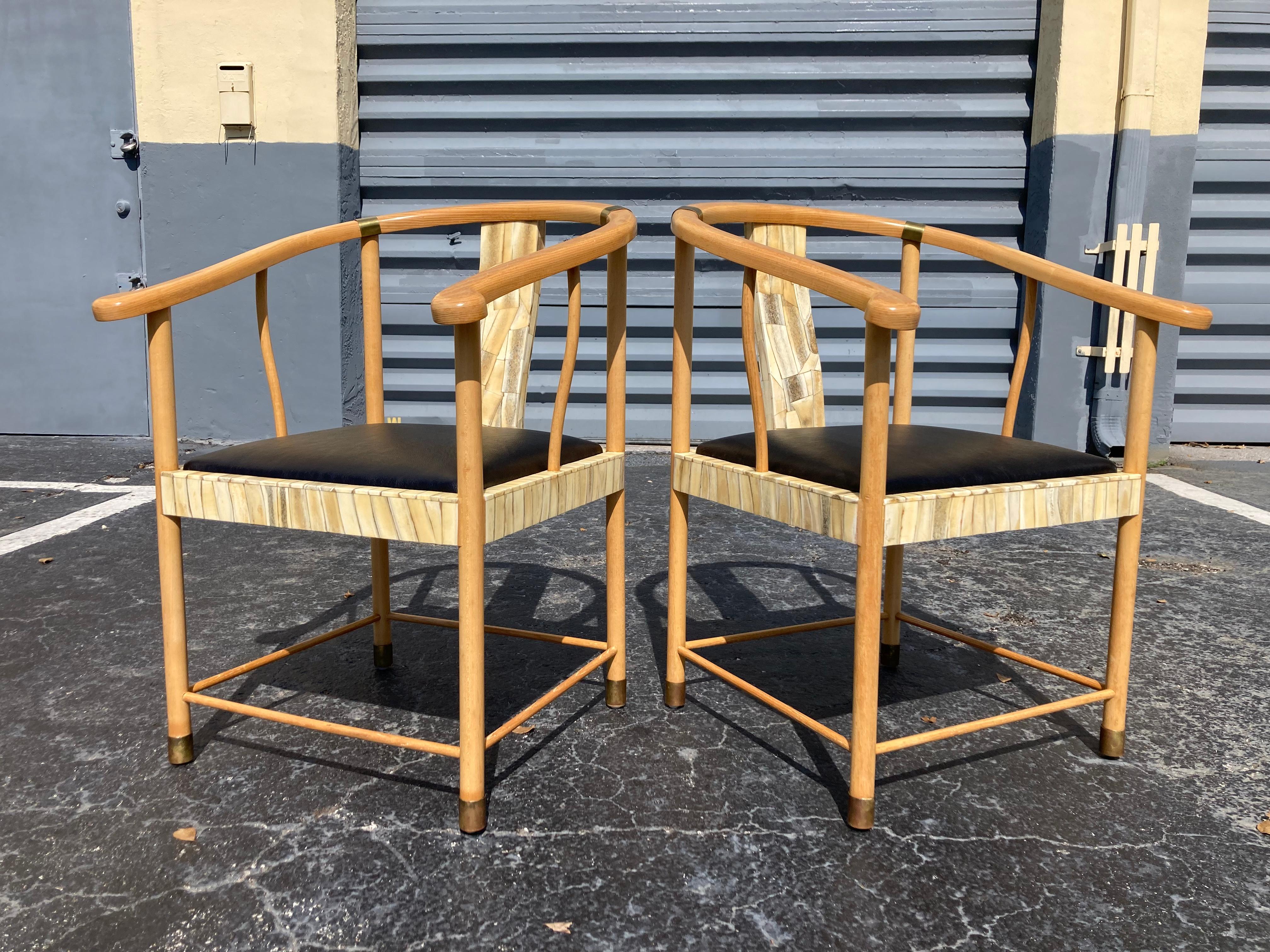 Fabulous pair of designer chairs with black leather seat cushions. Chairs are partly covered in bone with brass details. Please see all pictures. Four chairs in total available. Price is for the pair.