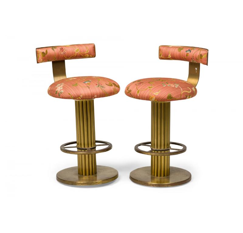 Paire de tabourets de bar pivotants en laiton de style américain du milieu du siècle, tapissés d'un tissu floral légèrement rayé de mauve, avec un dossier bas et incurvé, une épaisse base en colonne cannelée et un anneau de pied percé. (DESIGN/One)