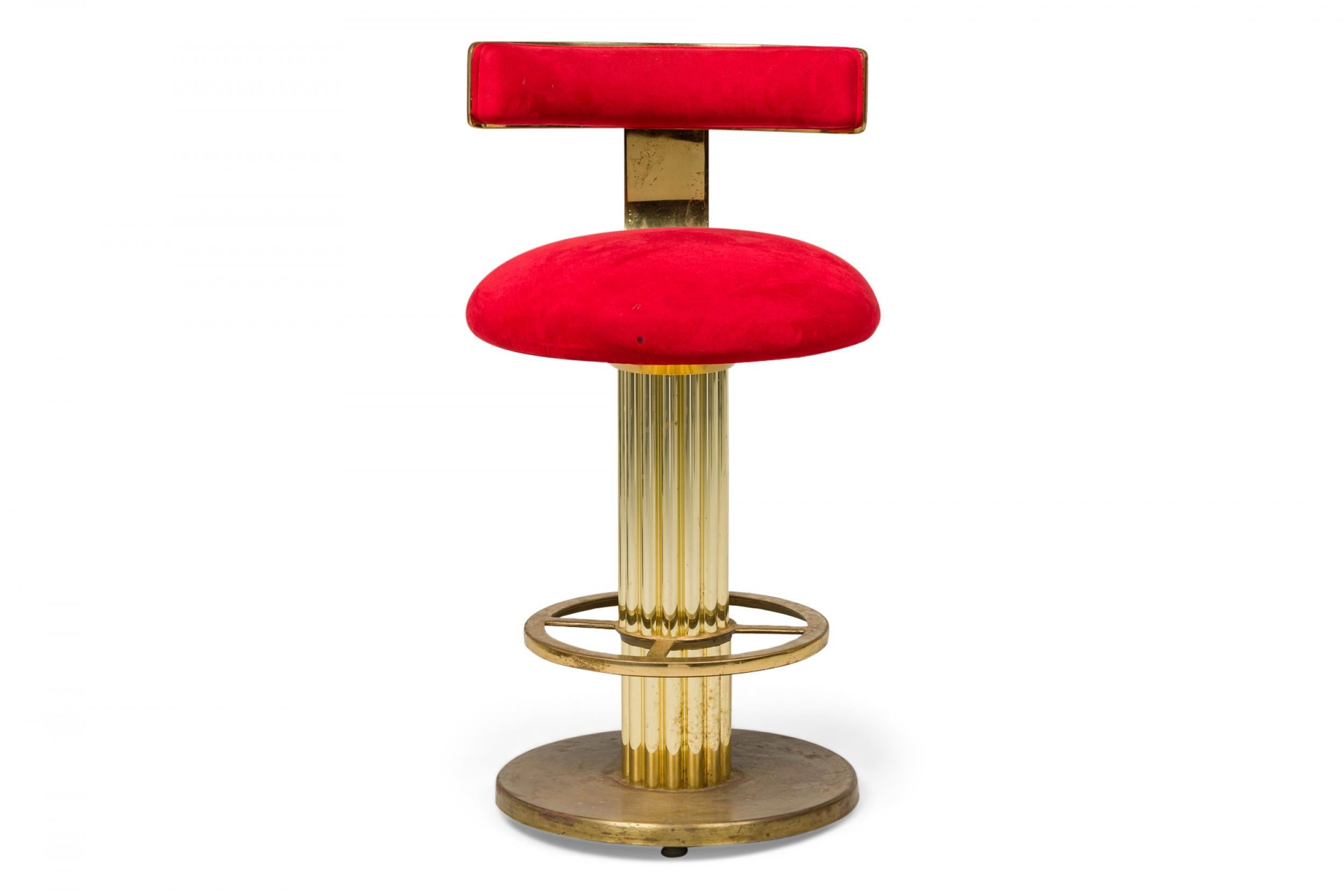 Pair of Mid-Century American brass swivel bar stools upholstered in a plush red fabric with low curved backrests, supported by thick fluted column bases plus pierced foot rings, resting on circular bases. (DESIGNS FOR LEISURE) (PRICED AS Pair)