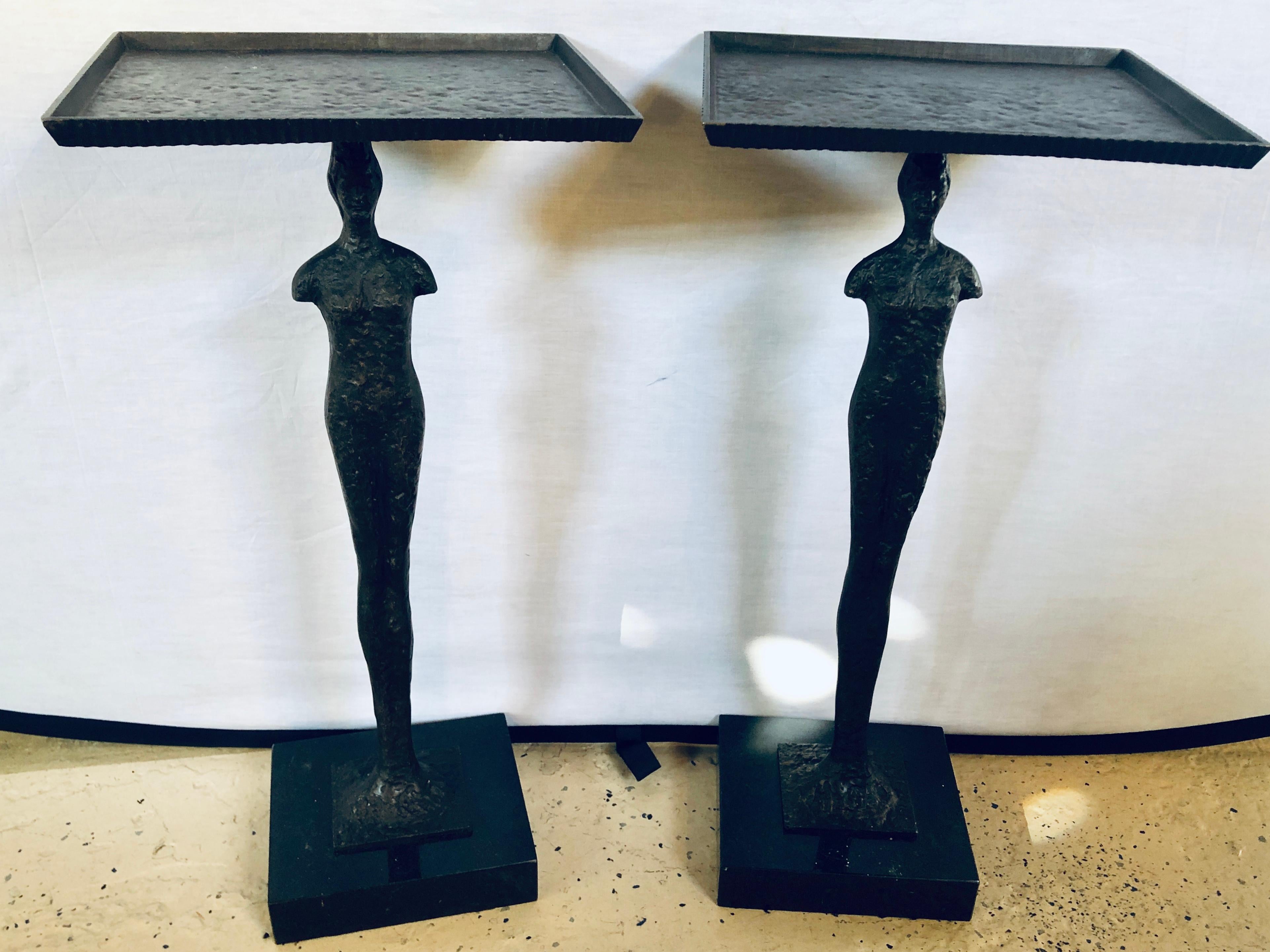 Pair of Diego Giacometti? style tray stands. Each having a single figure of a man with arms folded balancing a tray on his head. The pair standing on a think marble or granite base.