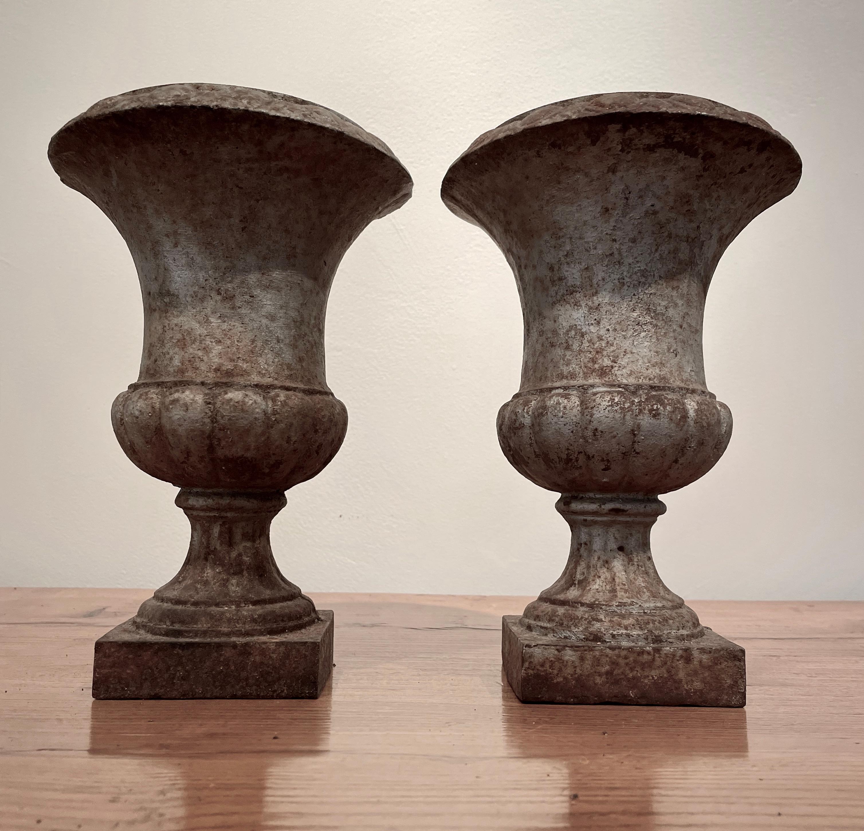 We love these French cast iron urns for their diminutive size, egg and dart rim, elegant form, and well-weathered original silver painted surface. In perfect condition, they would be beautiful holding dried or silk flowers on your bedside tables or