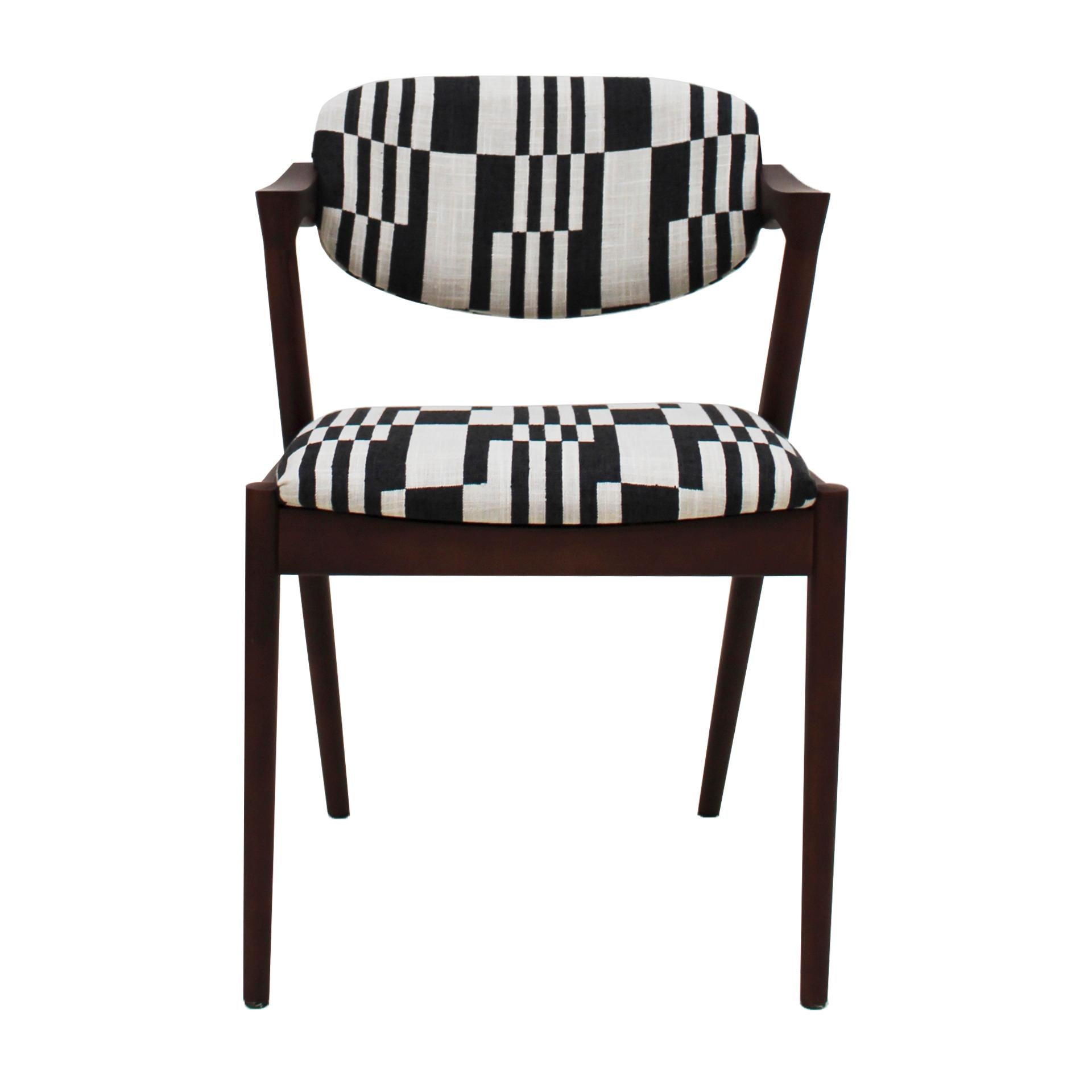 Cette chaise, inspirée des principes de conception associés à Kai Kristiansen, est dotée d'un cadre robuste en bois de noyer et d'un dossier inclinable pour un soutien ergonomique. Tapissé de lin avec un motif rectangulaire noir et blanc