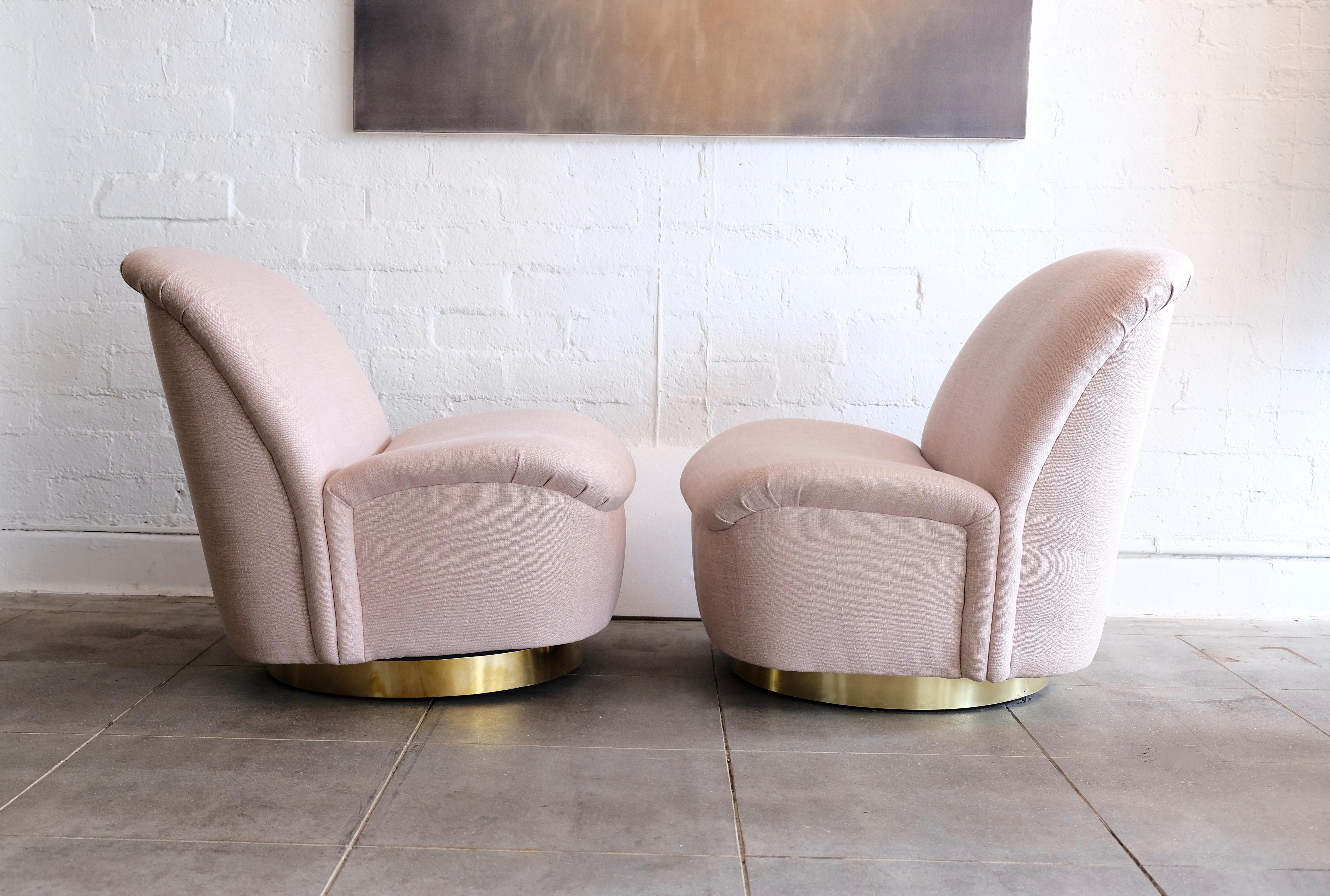 These pair of slipper chairs by Directional tilt and swivel on their brass base. The chairs have been freshly recovered in a pale blush pink fabric. The brass base is new since the original base was covered in the old fabric.