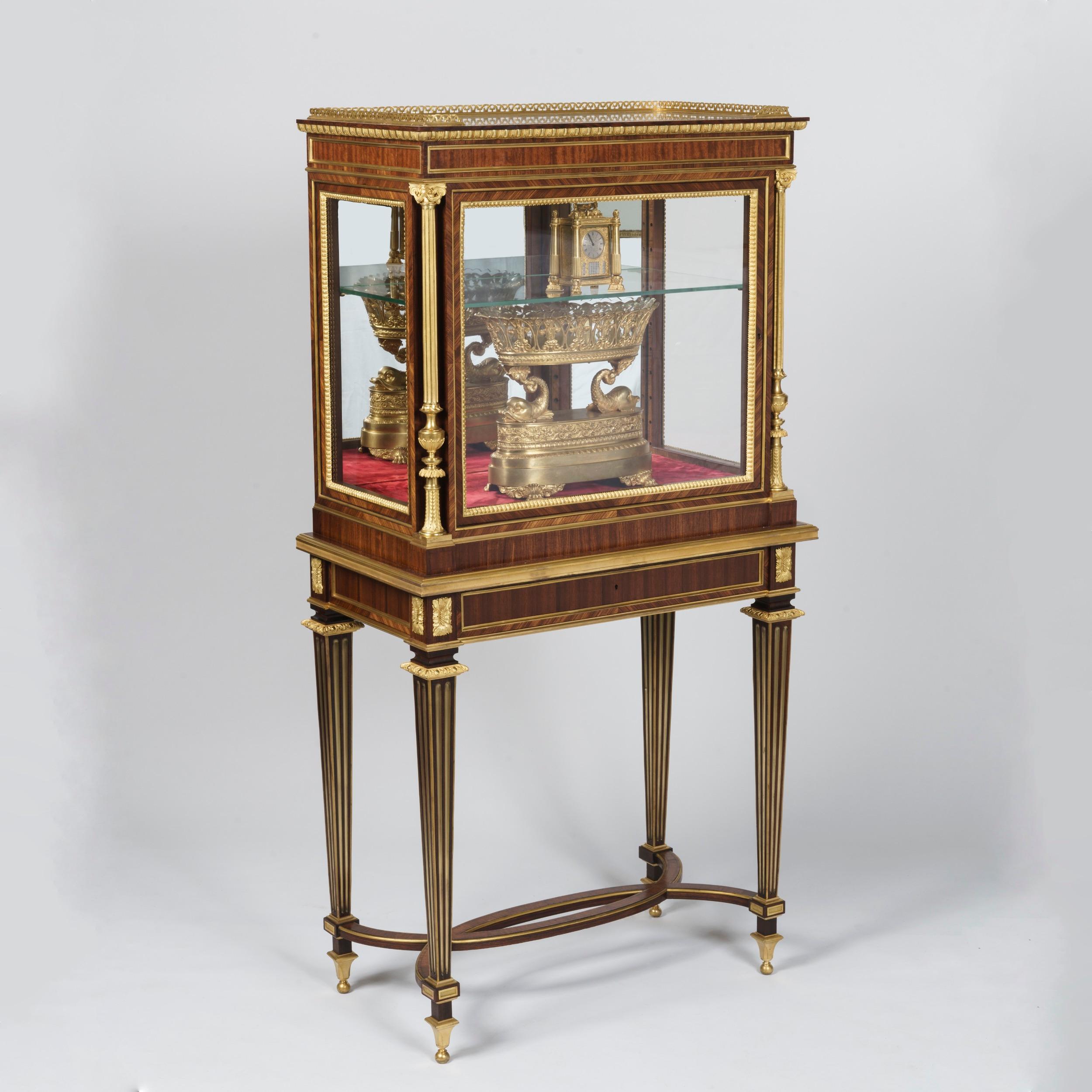 A Pair of Display Cabinets
In the Louis XVI Manner

Constructed from kingwood and bois satiné with ormolu mounts throughout, each cabinet supported on tapering square fluted legs with looped stretchers, the corners of the apron dressed with gilt