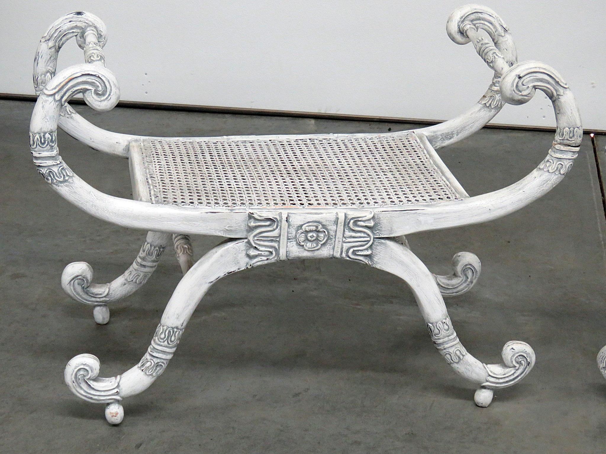 Pair of distressed painted curule benches with caned seats.