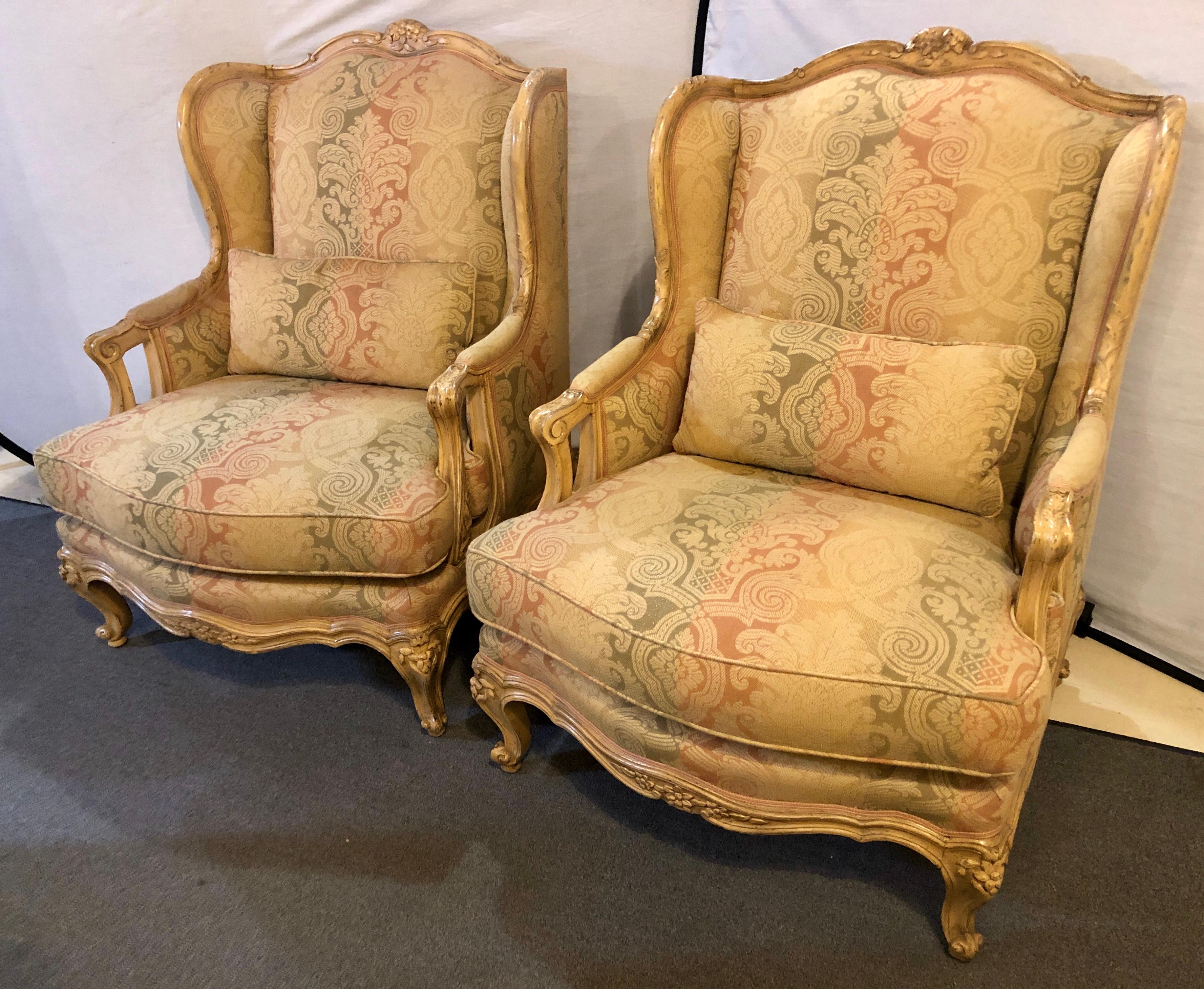 Pair of palatial Louis XV style wingback chairs. This fine pair of large and impressive distressed wingback or bergere chairs are finely carved with roses, leafs and vines on painted stylish strong and sturdy frames. The pair in a stunning stripped