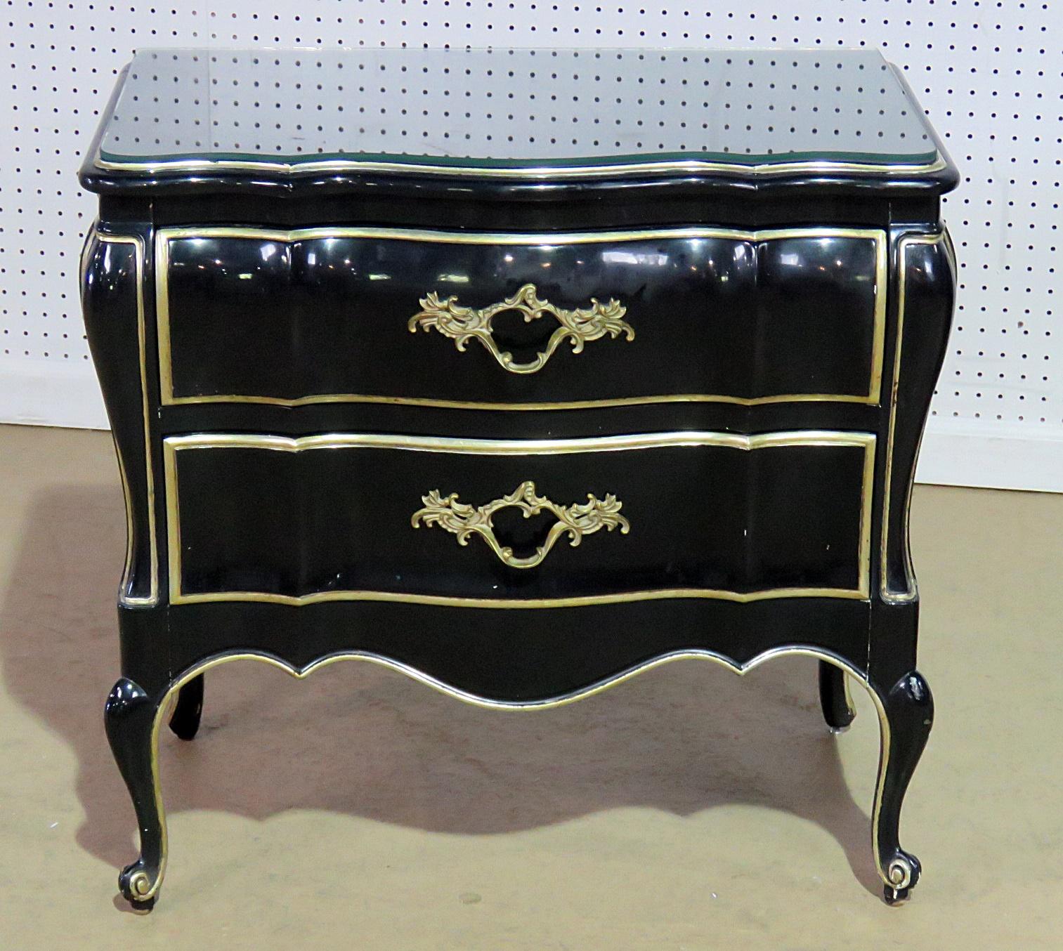 Pair of Dixon Powdermaker ebonized two-drawer nightstands with glass tops and gilt accents.