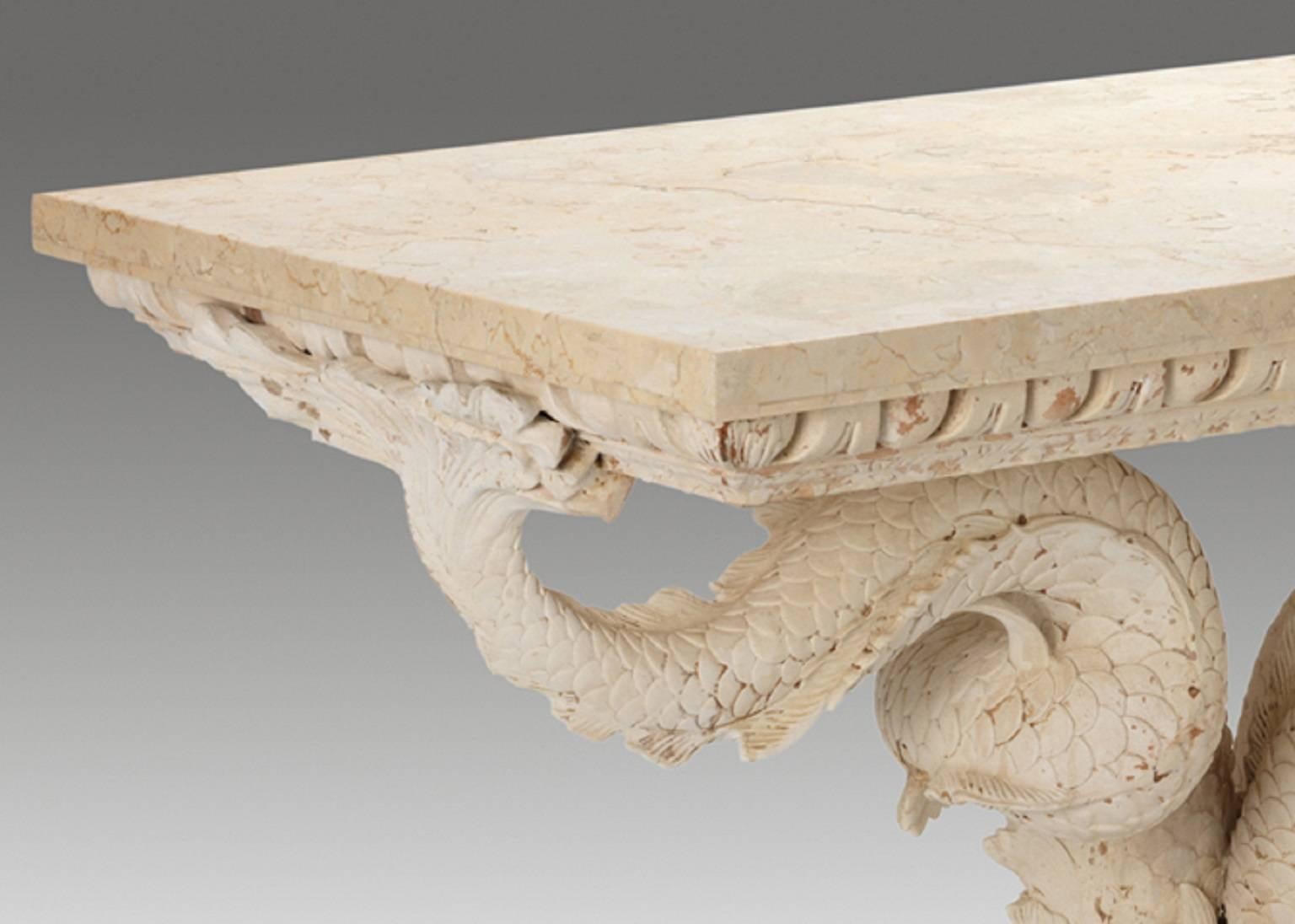 A fine pair of dolphin console tables designed in the style of William Kent, the marble tops resting upon an egg-and-dart frieze supported by a trio of stylized Kentian dolphins resting upon carved step work plinths.

This item is made to order.

We