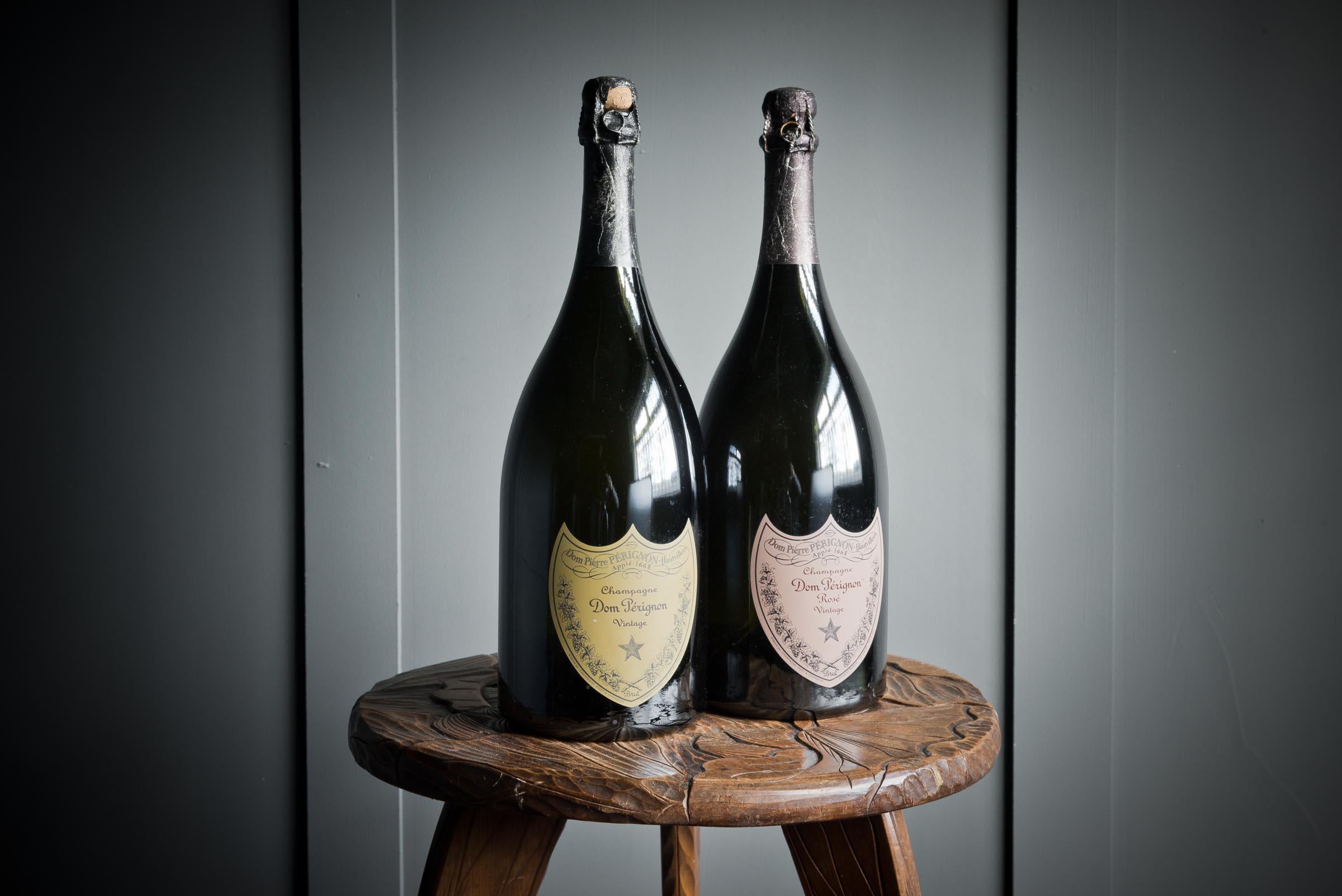 A pair of Dom Perignon dummy bottles, one Rose and one classic Dom perignon. Both are complete with cork and wire cork cap. 