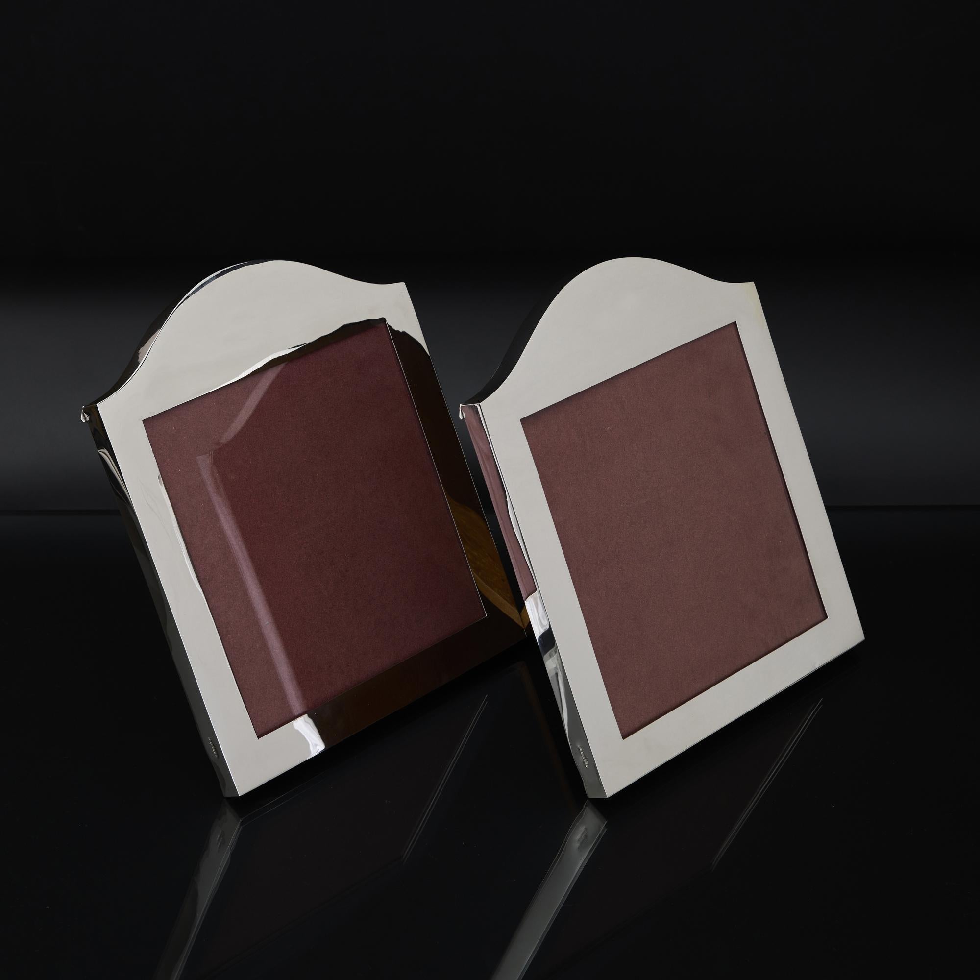 Pareja de marcos de fotos de plata hechos a mano con bordes anchos y parte superior abovedada. Son de una calidad especialmente buena y cada marco admite una foto casi cuadrada de 196 mm x 190 mm.  Peso: 685 g (22,02 onzas troy)