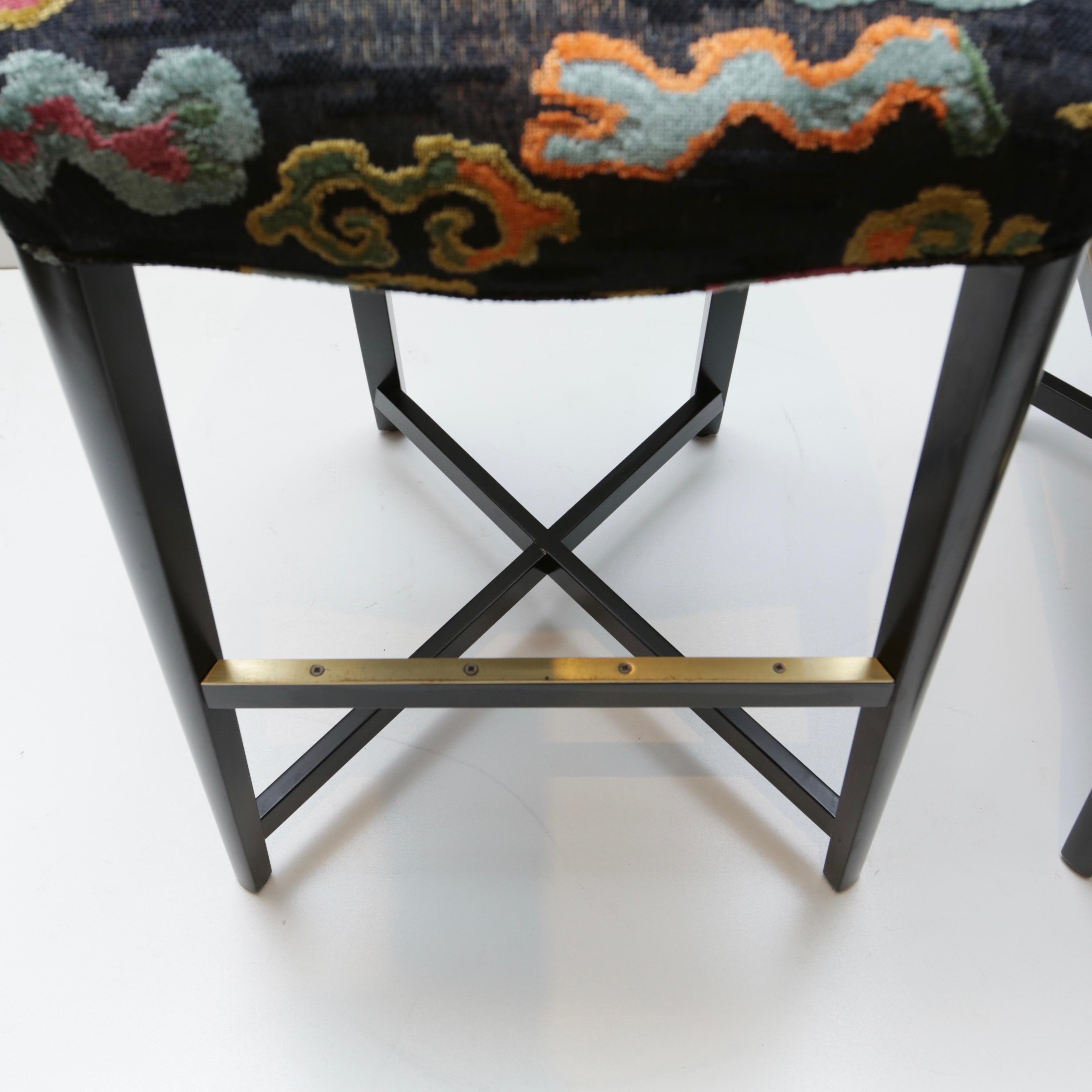 Not your average barstools. This rather striking pair are as standout as Donghia designs are known to be. Ebonized wood frame with brushed brass footrest inserts.