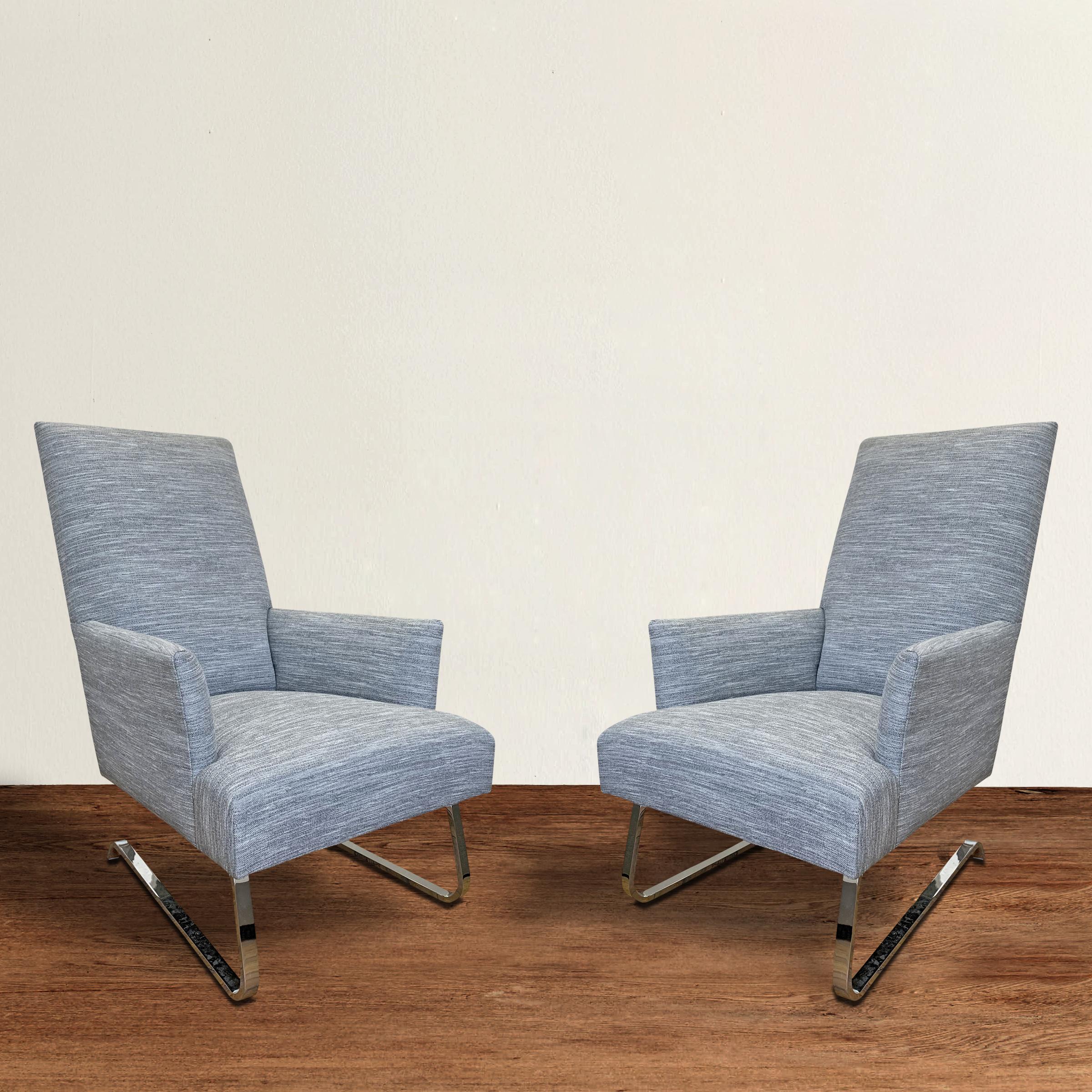 A pair of brand new Donghia Odeon armchairs of cantilevered form with polished chrome legs that allow for a slight bounce, and upholstered in a beautiful variegated gray wool. Chairs are perfect for lounging, but comfortable enough to use as dining