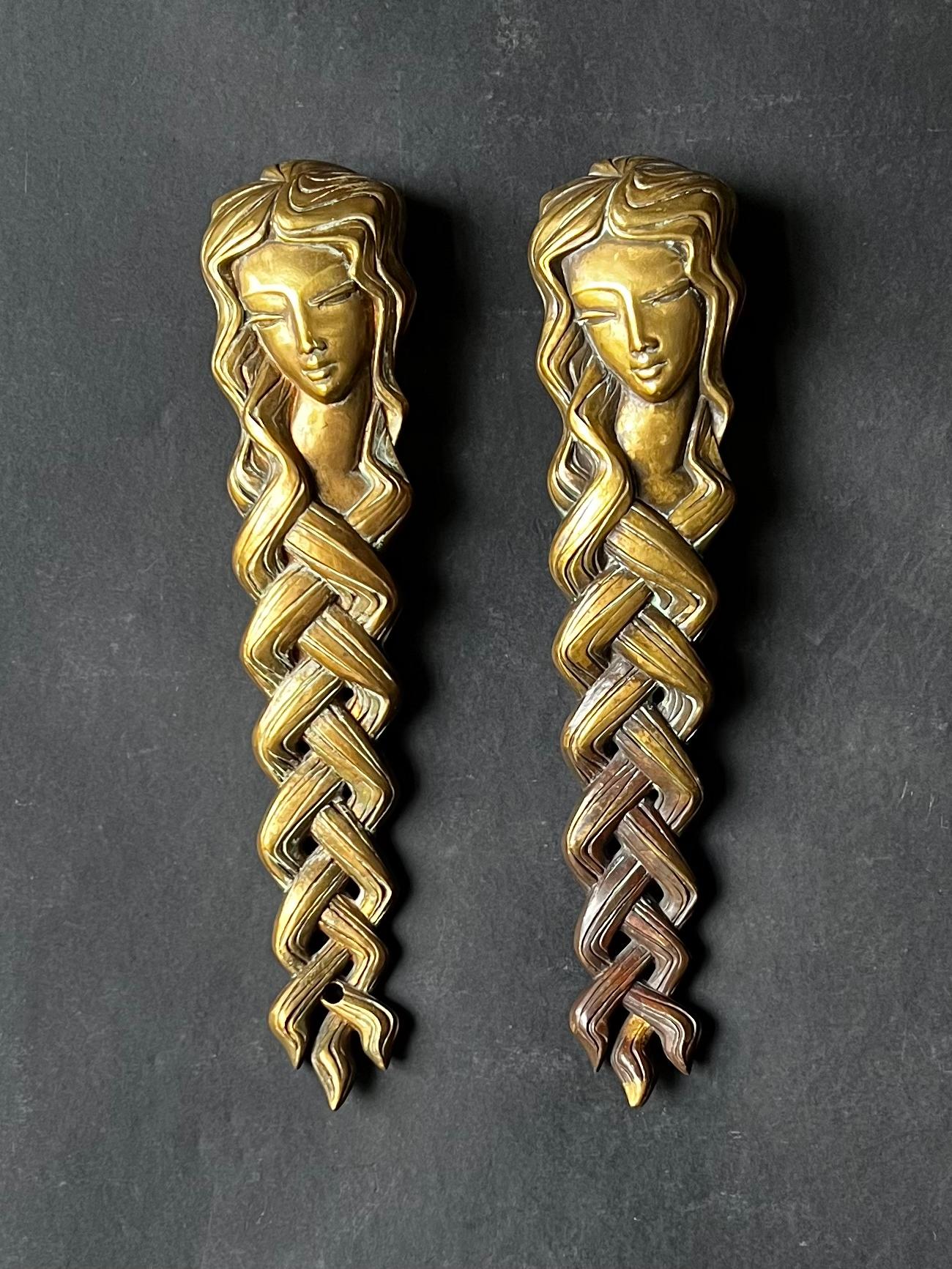 A pair of heavy bronze or brass door handles in the form of a woman's face with long braided hair. 20th century, found in Germany.

Beautifully made pieces, each of the same design. The shape is slightly curved - as seen in profile - and the
