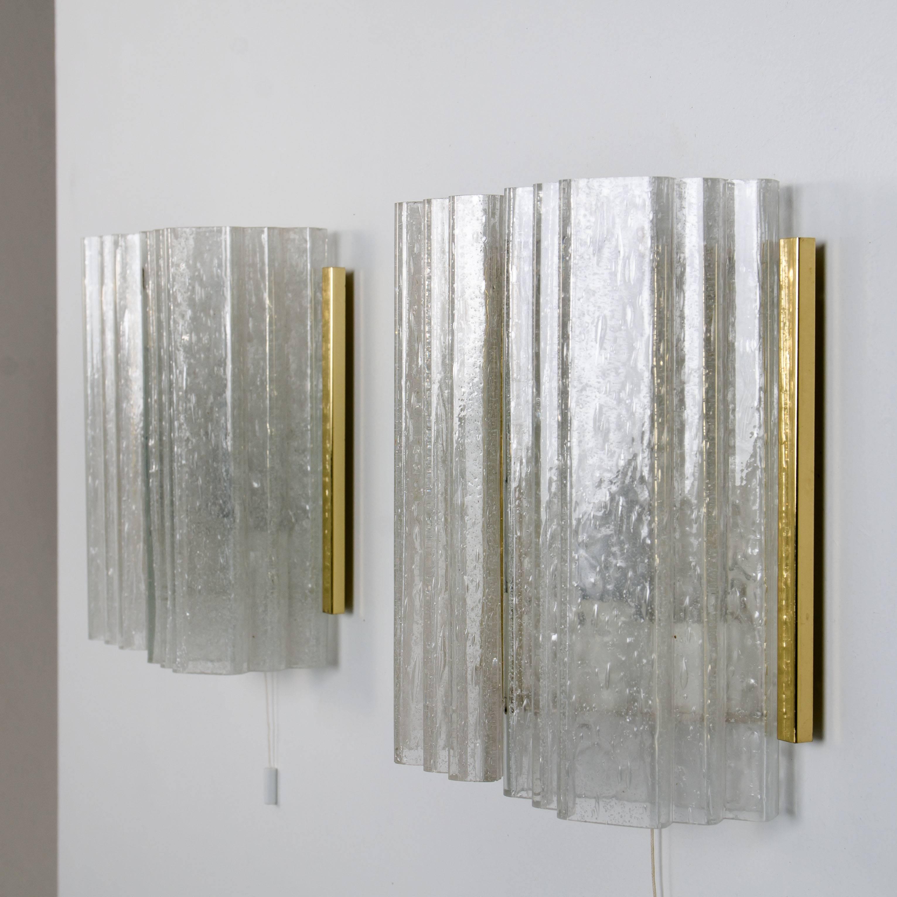Estos apliques de pared han sido diseñados por Doria. Cada aplique es de metal pintado en blanco con detalles de latón y tiene dos gruesas tulipas de cristal soplado a mano. Los tonos de cristal de alta calidad reflejan maravillosamente la luz.