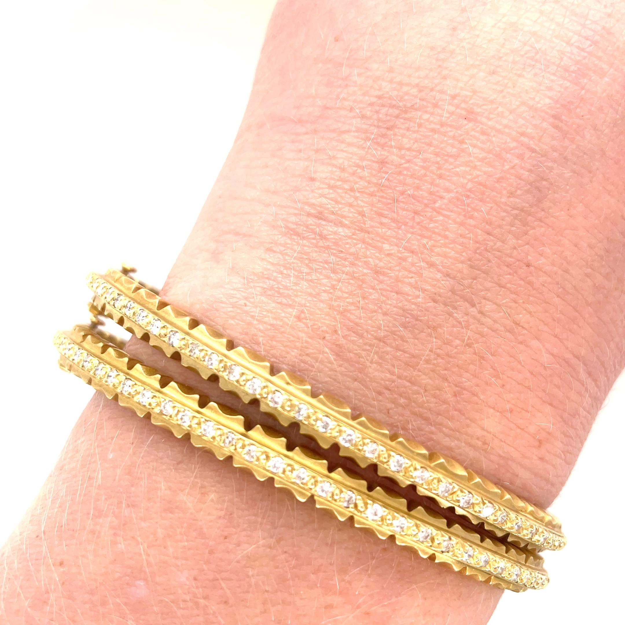 Paire de bracelets à charnière en diamant de Doris Panos. Ces bracelets très agréables à porter sont dotés d'un motif amusant qui court le long des bords. Le centre est serti de 66 diamants ronds de taille brillant pesant environ 0,85 carat au