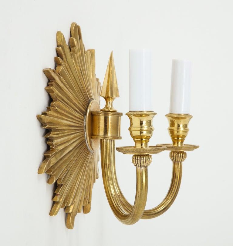 A pair of brass double-arm sconces with a lovely sunburst black plate and beautiful detailing throughout, including fluted arms and intricate etching on the bobeches (base supporting the lights). These would be perfect in an entry, dining room,