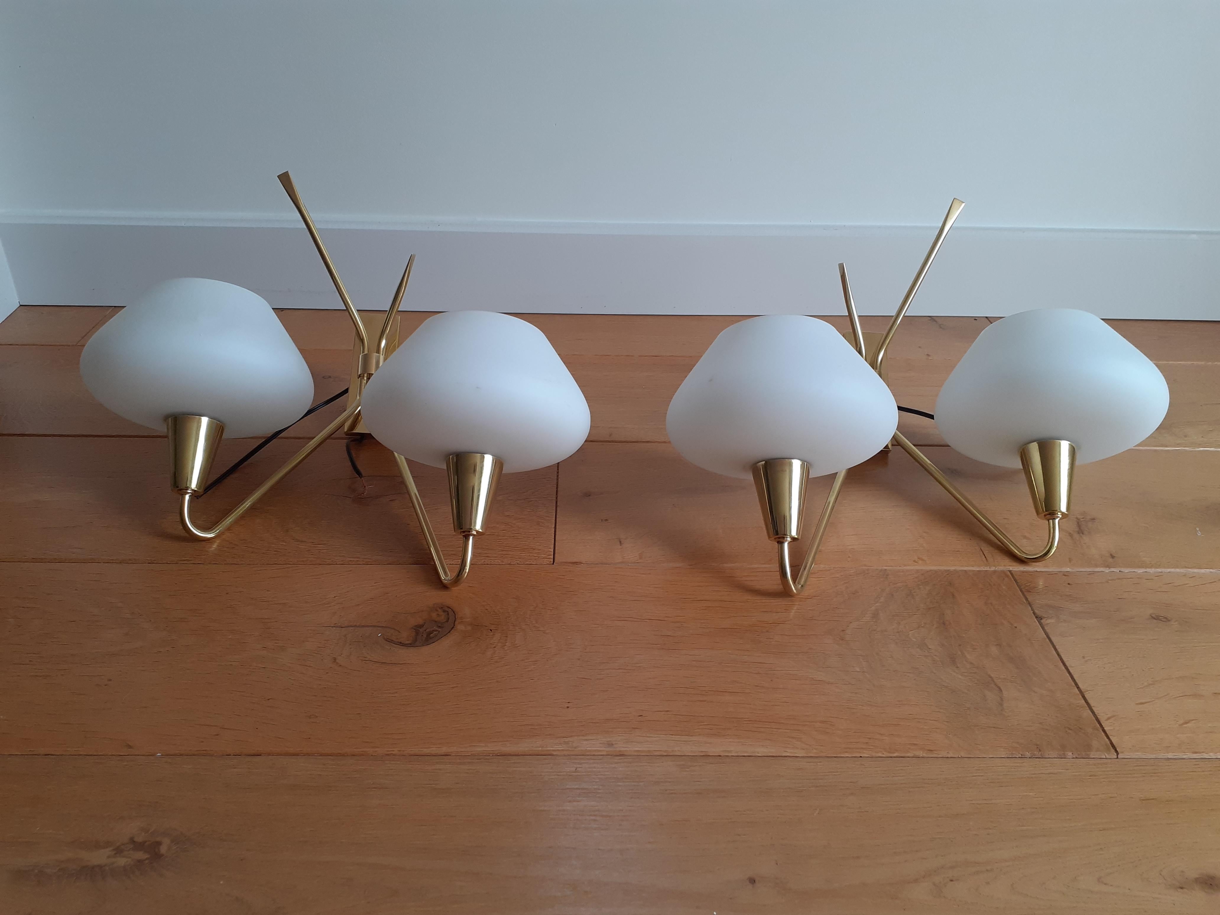 Pair of double brass and opaline glass wall lights consisting of a rectangular brass base on which are fixed two brass light arms ending in a conical support surmounted by a flared shade in white opaline glass.
New cabling to EU standard.
French