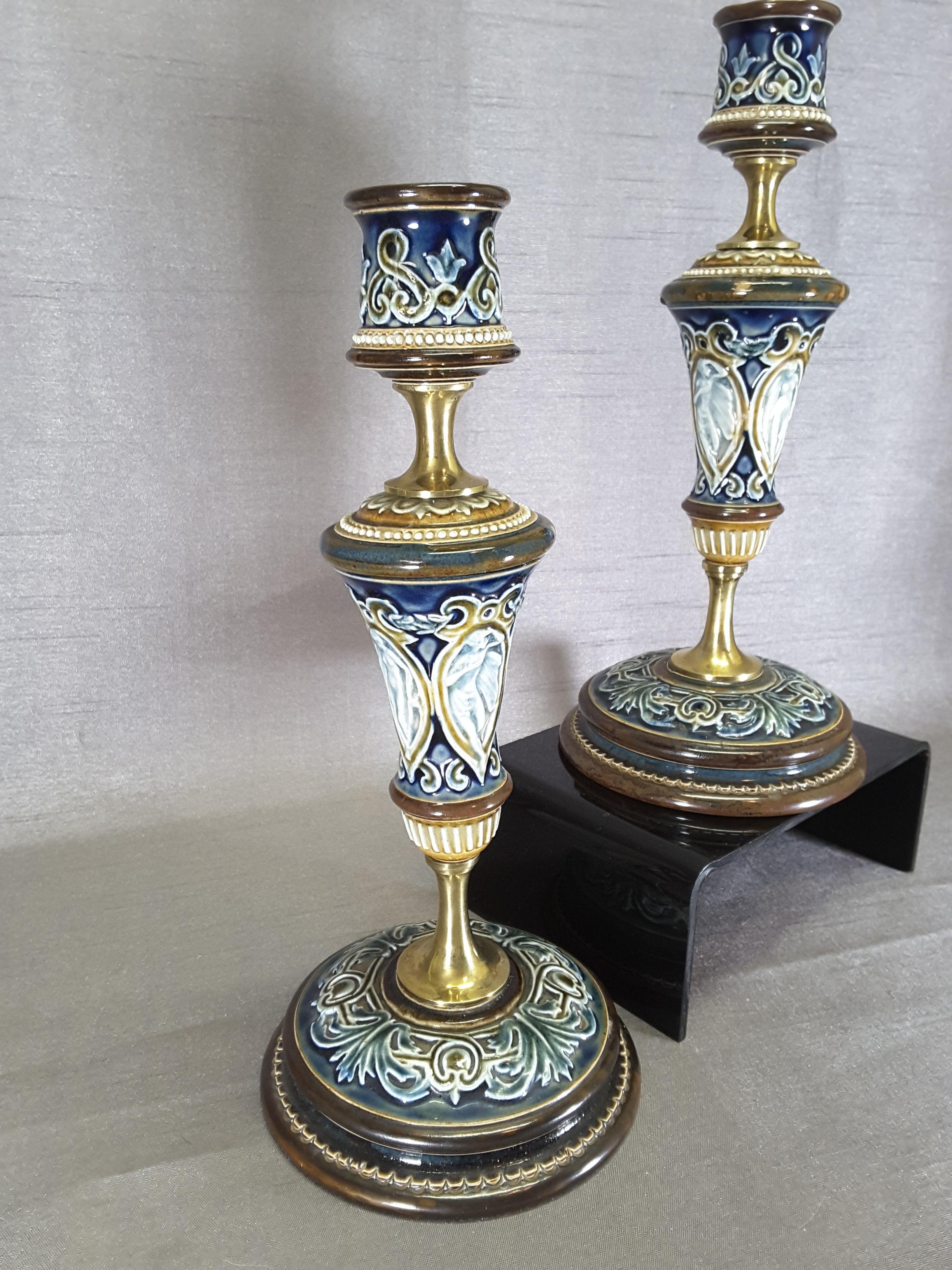 Pair of Doulton Lambeth Candlesticks, circa 1890.

Stoneware and brass spacer mounts, Decorated with winged angels in a stylized cartouche. The Candlesticks are done in browns, coffee beige and blues. Numerous impresse marks on the bottom, Doulton