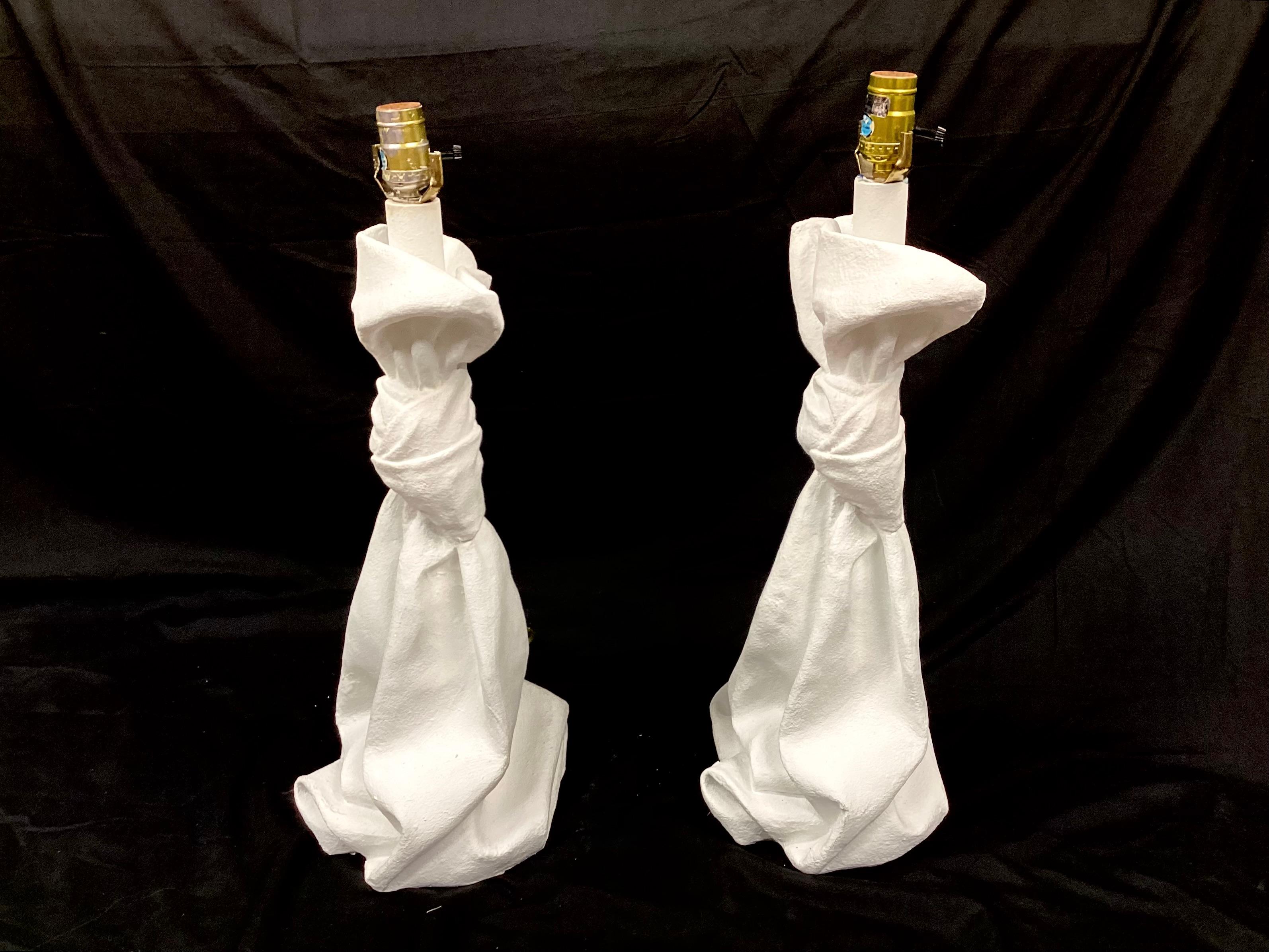 Pair of 20th century plaster table lamps in the John Dickinson style of the 1970s. Draped and knotted, these unique lamps appear sculptural in design.  These heavy and sturdy lamps are in good working condition and will make a statement in any