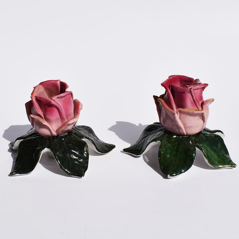 Set of two ceramic Dresden floral rose tole candleholders. This beautiful of candle stick holders are ceramic and created to resemble pink rosebuds with lush green leaves. Each candlestick features a bright pink rosebud with slightly parted leaves.