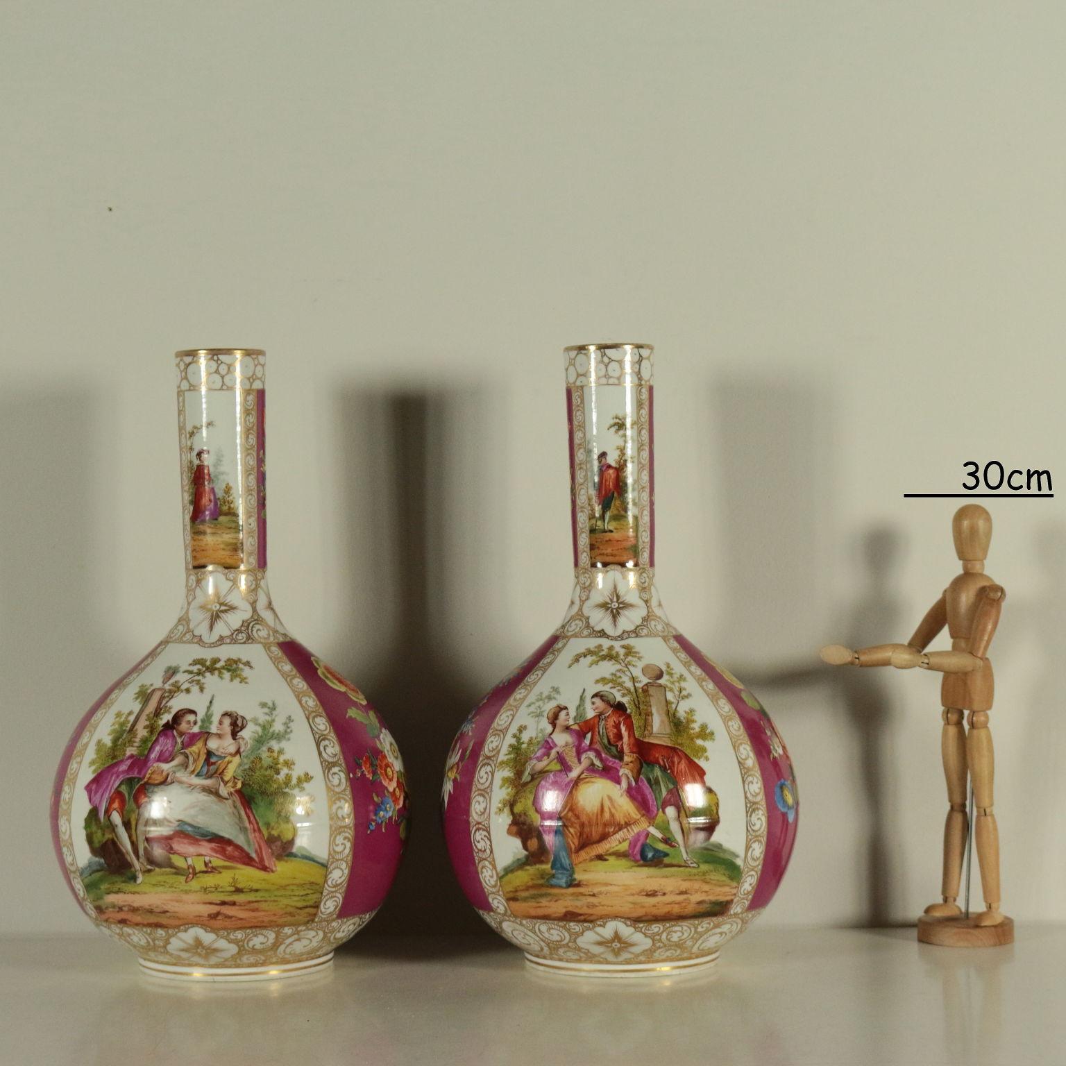 Pei of porcelain vases with long neck and gilded decorations that create reserves. Painted with bouquets, figures and lovely scenes with a landscape in the background. Manufacture's brand under the base.