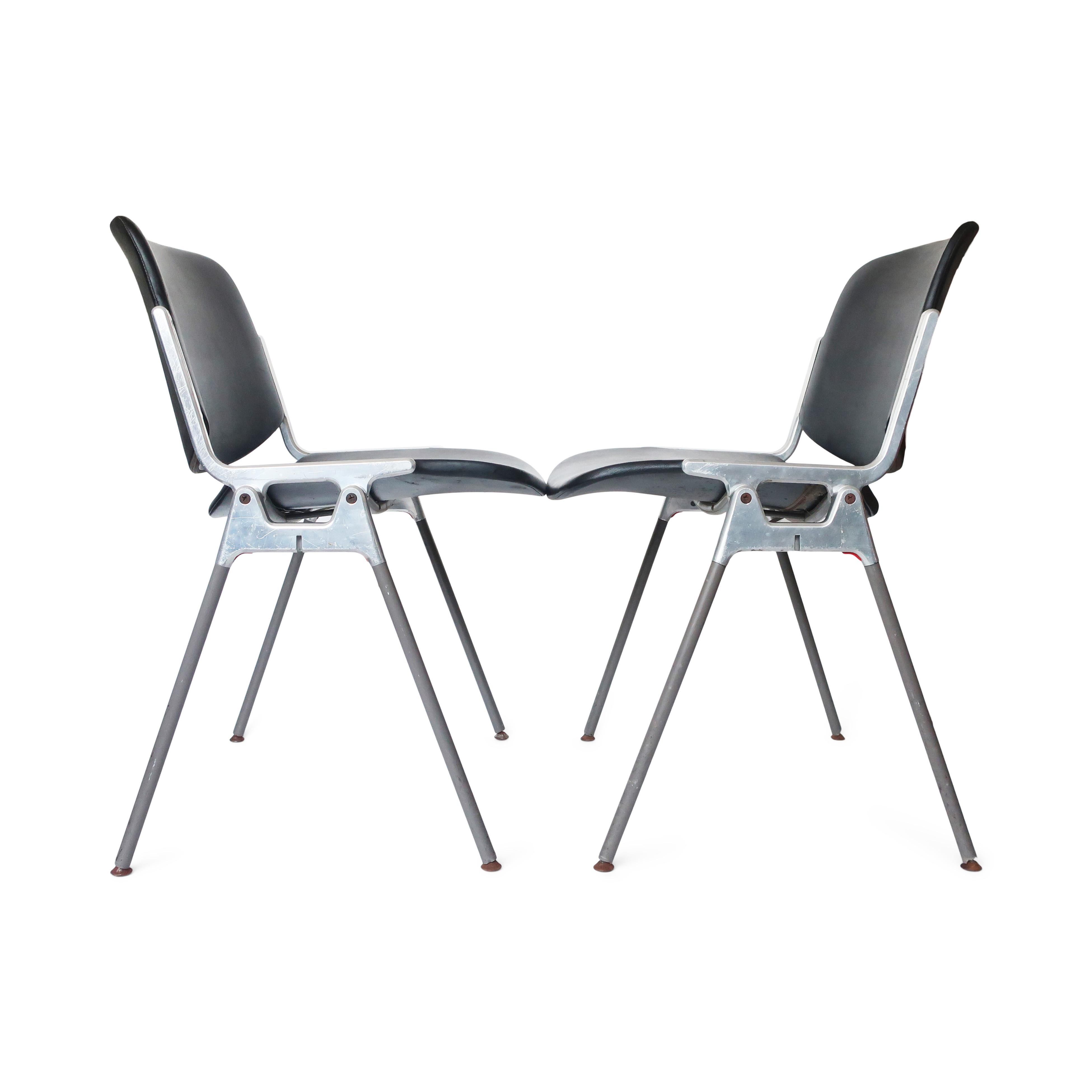 A pair of Italian Modern DSC 106 chairs designed by Giancarlo Piretti for Castelli. The sleek modernist design utilizes molded seats and backs upholstered in dark gray vinyl on a polished aluminum frame with angled grey painted legs. Super