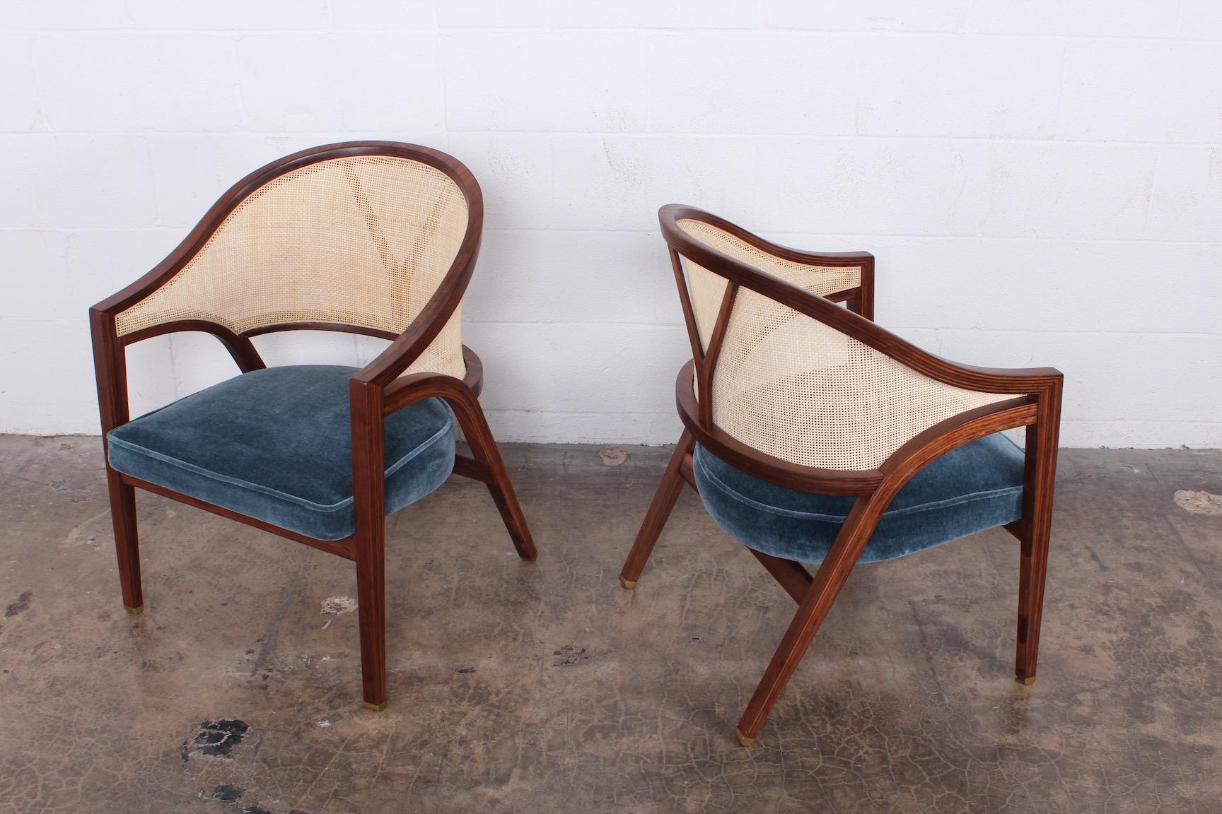 A pair of cane back lounge chairs with brass feet and mohair upholstery.