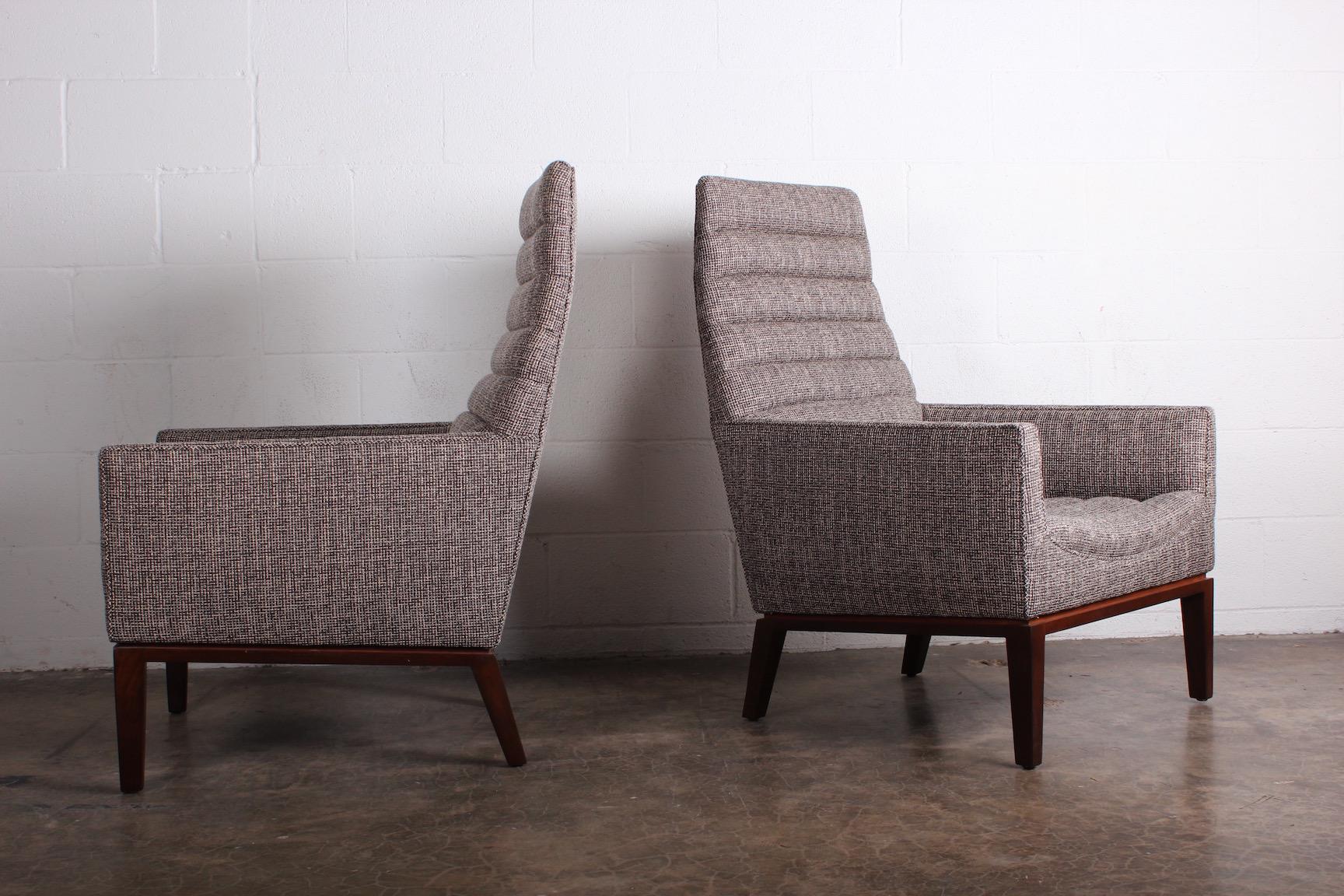 A pair of high back lounge chairs with mahogany bases. Designed by Edward Wormley for Dunbar.