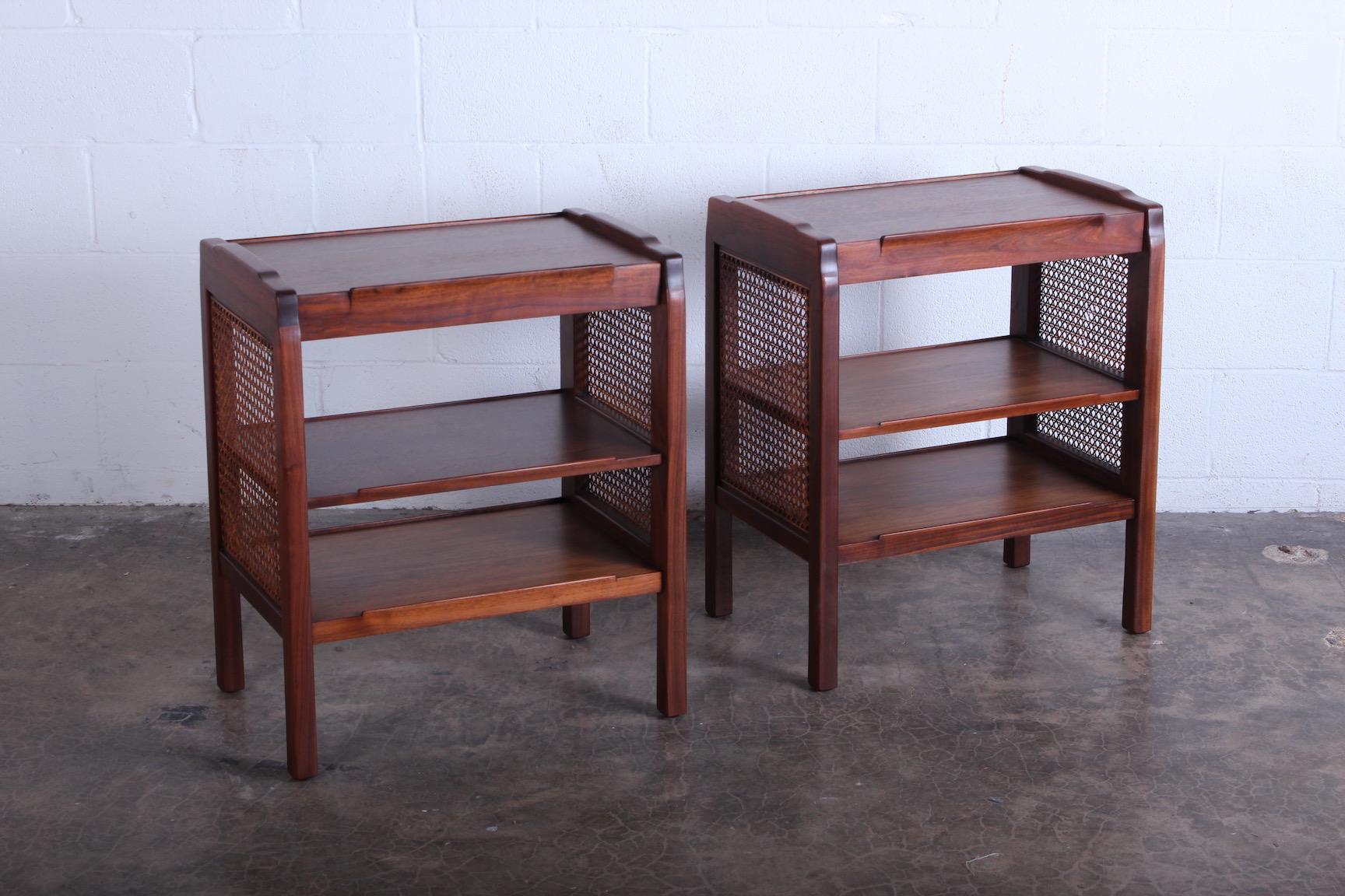 A pair of walnut nightstands with cane sides. Designed by Edward Wormley for Dunbar.