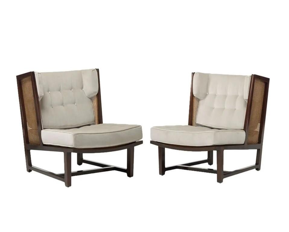 A rare pair of Dunbar Wingback Model 6016 lounge chairs in sculpted mahogany and woven cane designed by Edward Wormley. An updated take on the classic wingback design, delivering an architectural silhouette. Completely restored. Each chair sits low