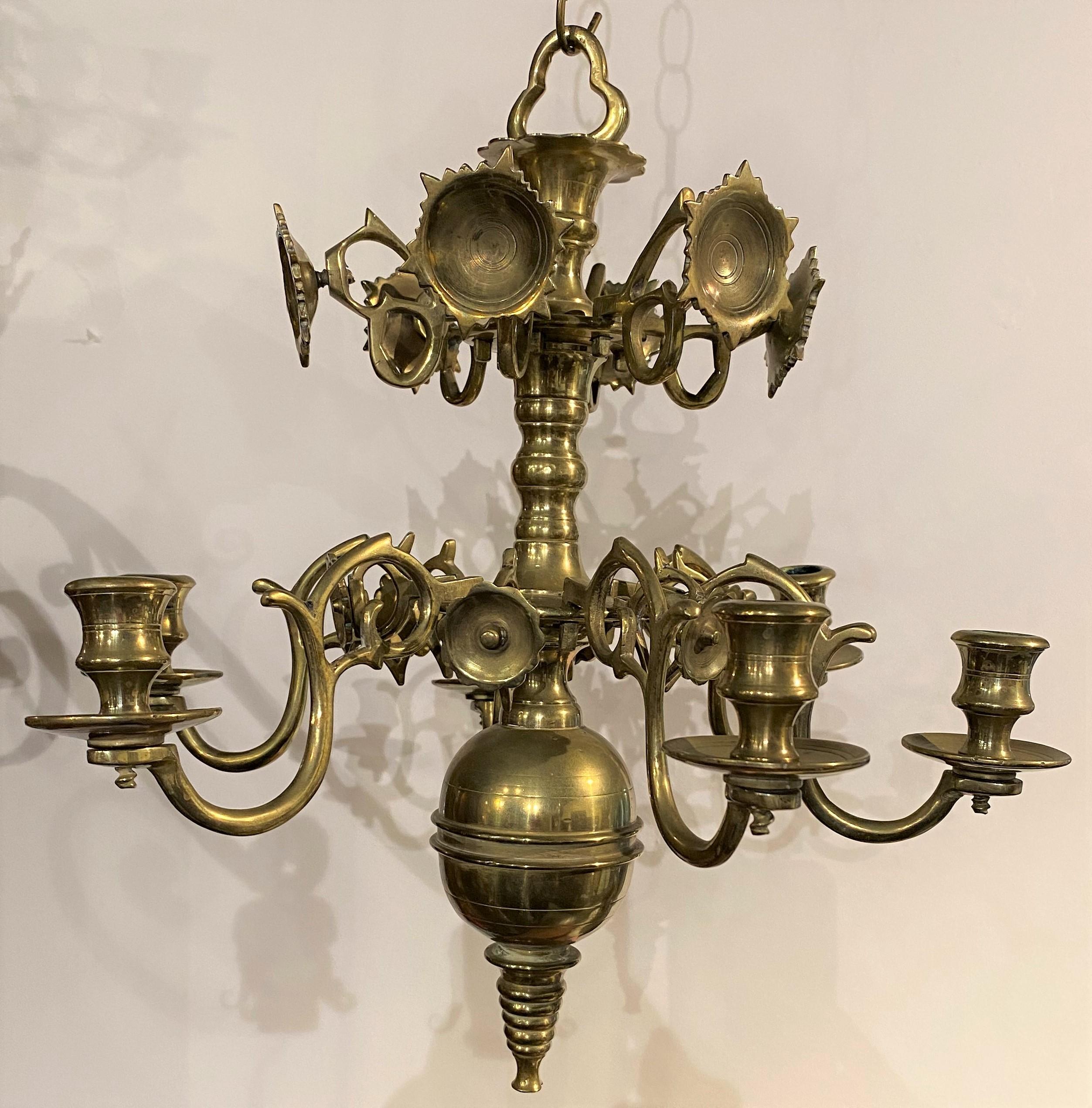 A fine pair of 18th or 19th century diminutive Dutch brass chandeliers, each with central baluster issuing six lamp or candle arms with drip pans on the lower tier, tapered ringed finial extending down from a brass ball, and six sunbursts on the