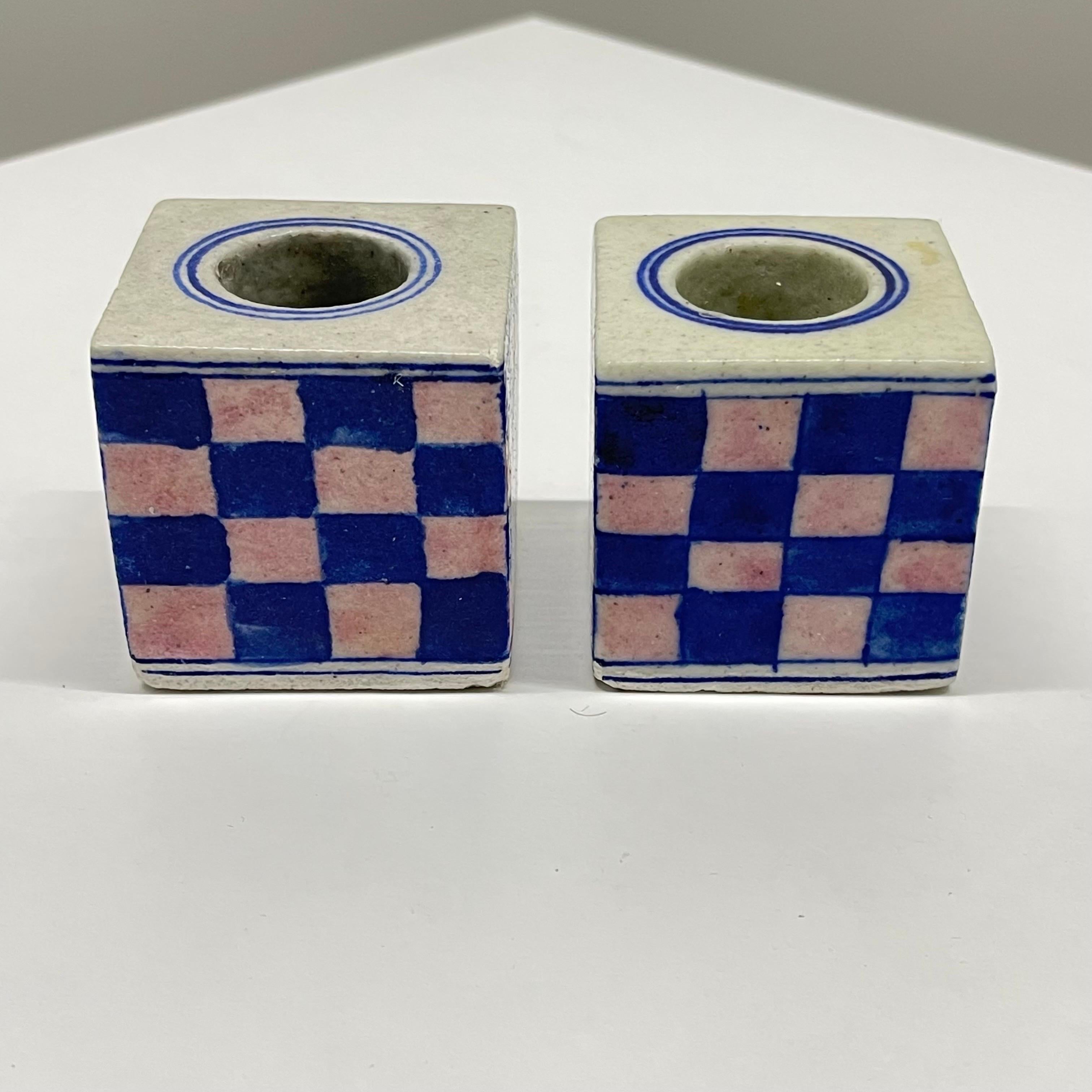 Exquisite pair of turn of the century Dutch Delft candlestick holders, rendered in unique square design with pink and blue checkerboard pattern over a cream glazed base. Europe, 1900s.