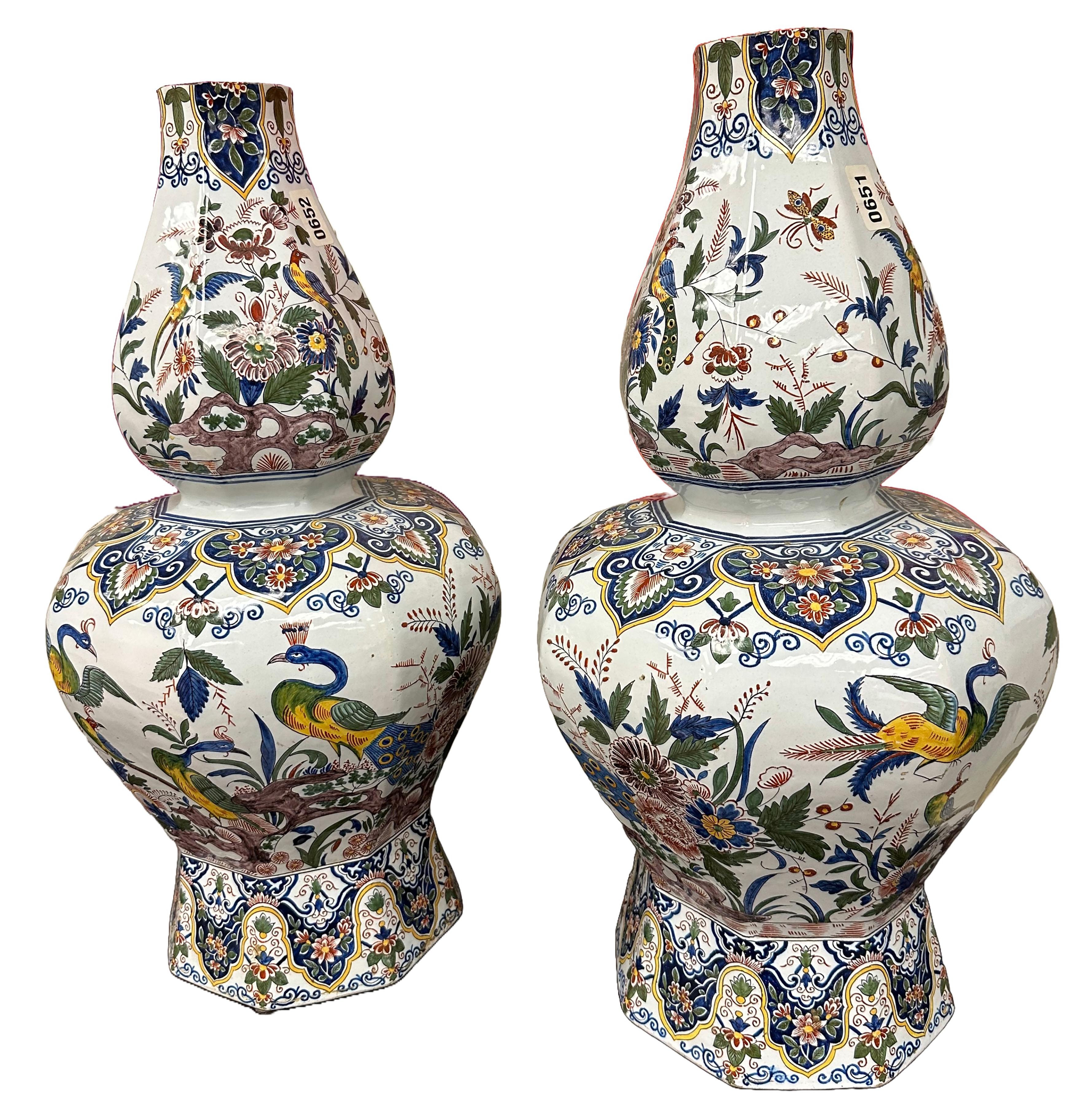 A beautiful pair of Dutch Delftware Polychrome glazed porcelain vases. Ornately rendered patterns and peacocks adorn in Blue, yellow, white, and green. This set of Chinoiserie style pottery appears to have some stylistic influences from China and