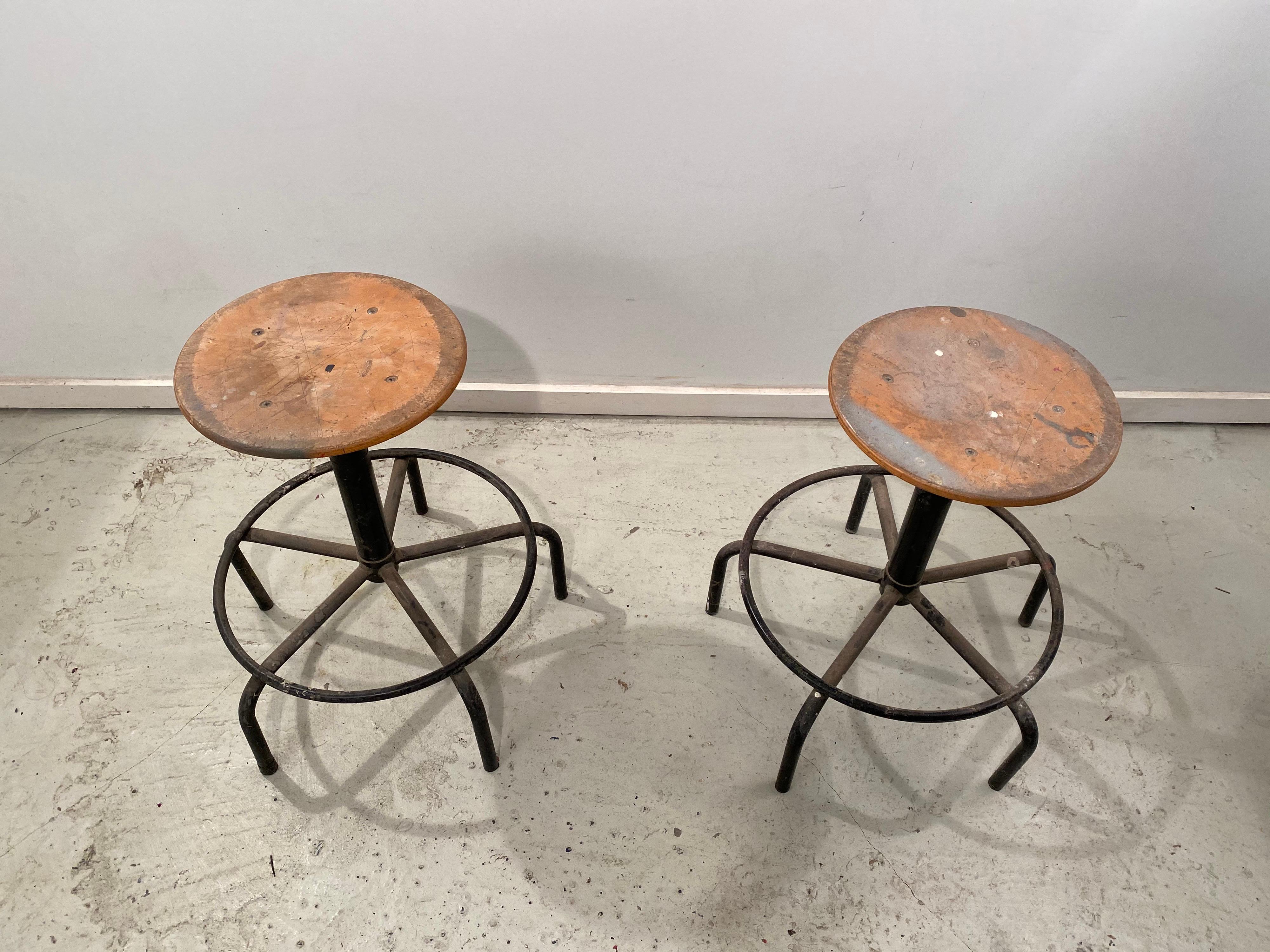 Beautiful industrial stools with a large base and wide legs for optimal stability, a swivelling and in height adjustable hard-wood seat. Deliberately not cleaned, because of the beautiful patina all-over, upon request they can be also be fully