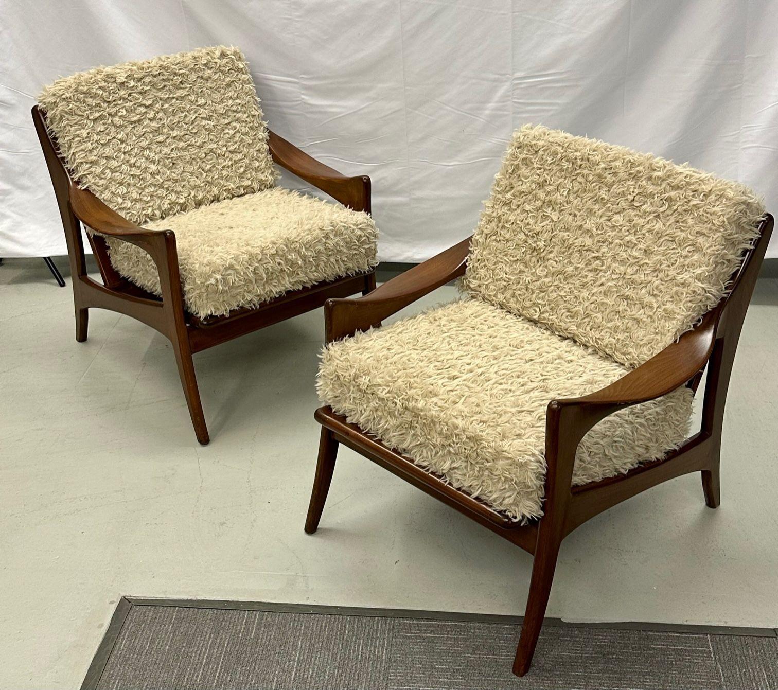 Pair of Dutch Mid-Century Modern style arm / lounge chairs, teak, brass
Pair of modern lounge chairs having a solid organc shape teak frame with brass accents. The cushions are newly stuffed and finished in a shaggy faux fur fabric.
 
Teak,