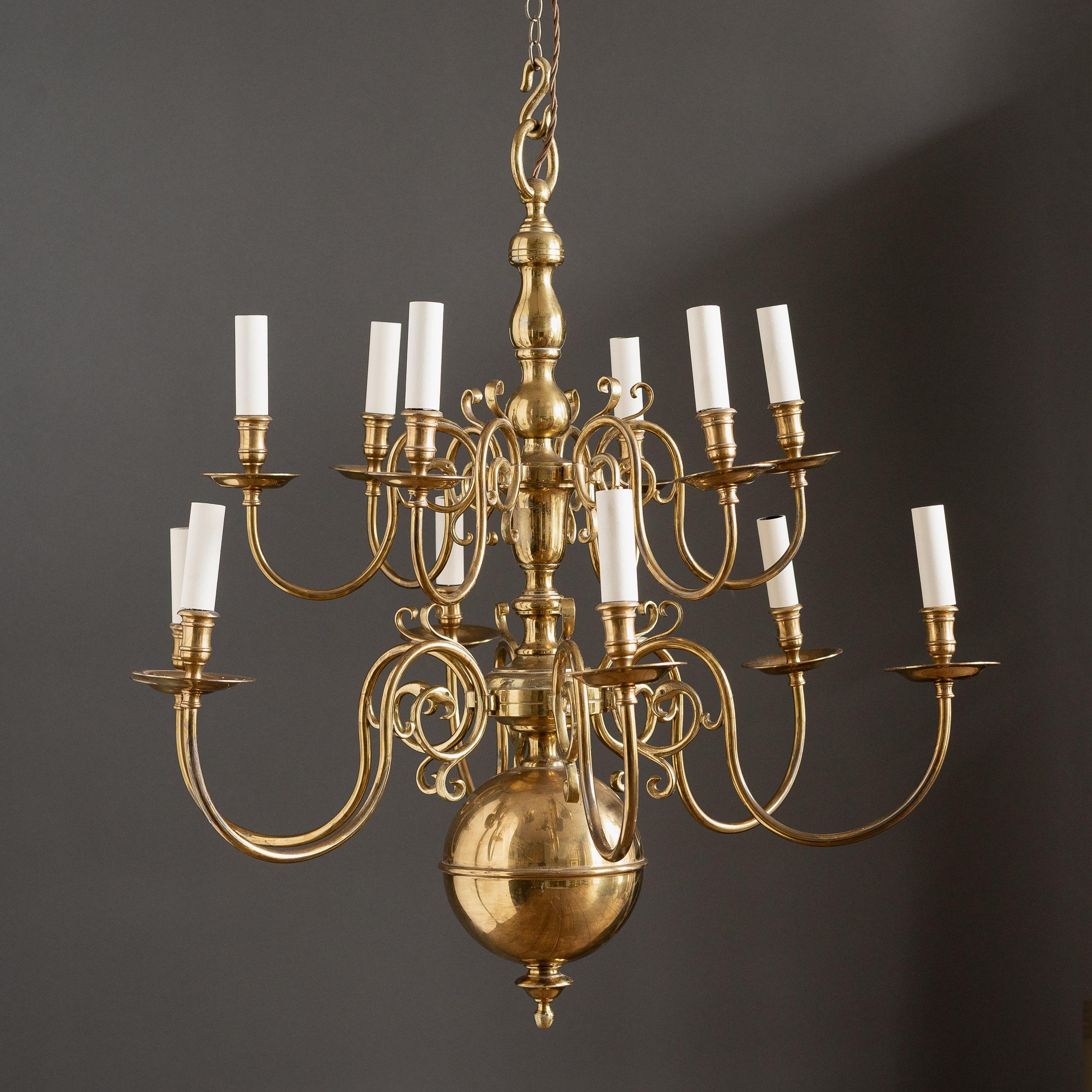 A pair of Dutch style brass chandeliers, mid-twentieth century in the early eighteenth century manner, each with two tiers of six branches, the old lacquered surfaces showing some signs of wear.

Re-wired and PAT tested to UK standards. Each