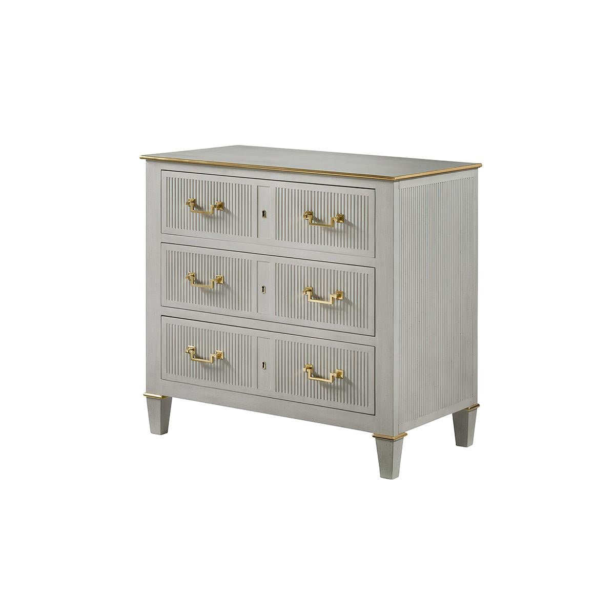 The Transitional Painted Bedside chest is fitted with three drawers and has an antiqued painted finish. With brass molded trim, the design features fluted drawer fronts and side panels, with solid brass Neo Classic drawer pulls and raised on short