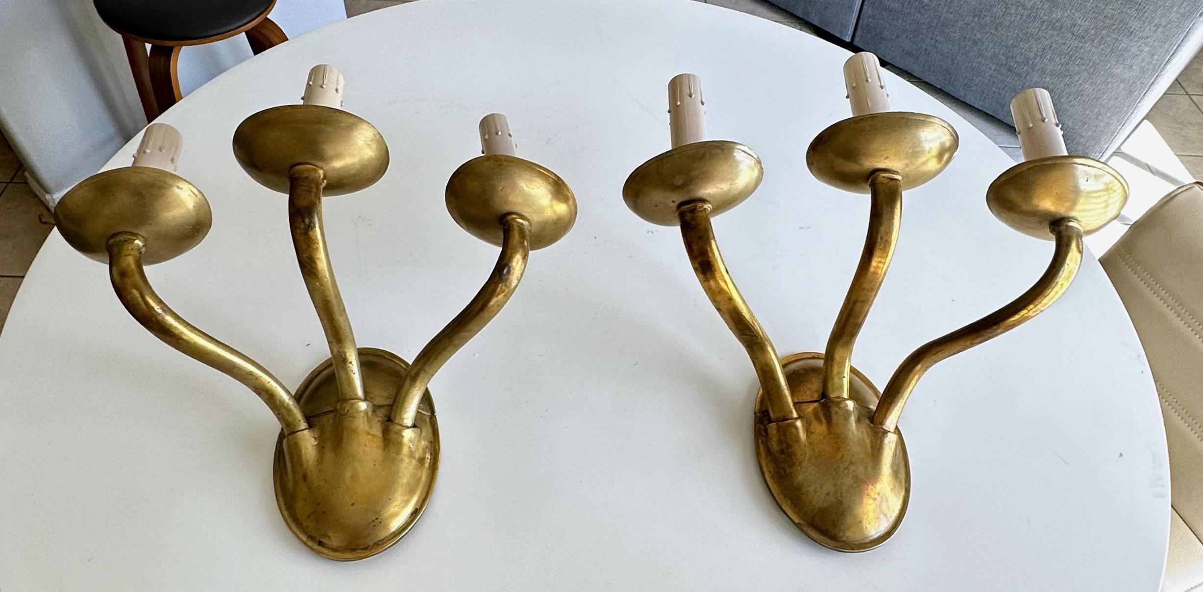 Pair of large and heavy solid brass or bronze three-arm wall sconces in the Arts & Crafts style by E F Caldwell, New York. Each sconce is stamped twice with the Caldwell 