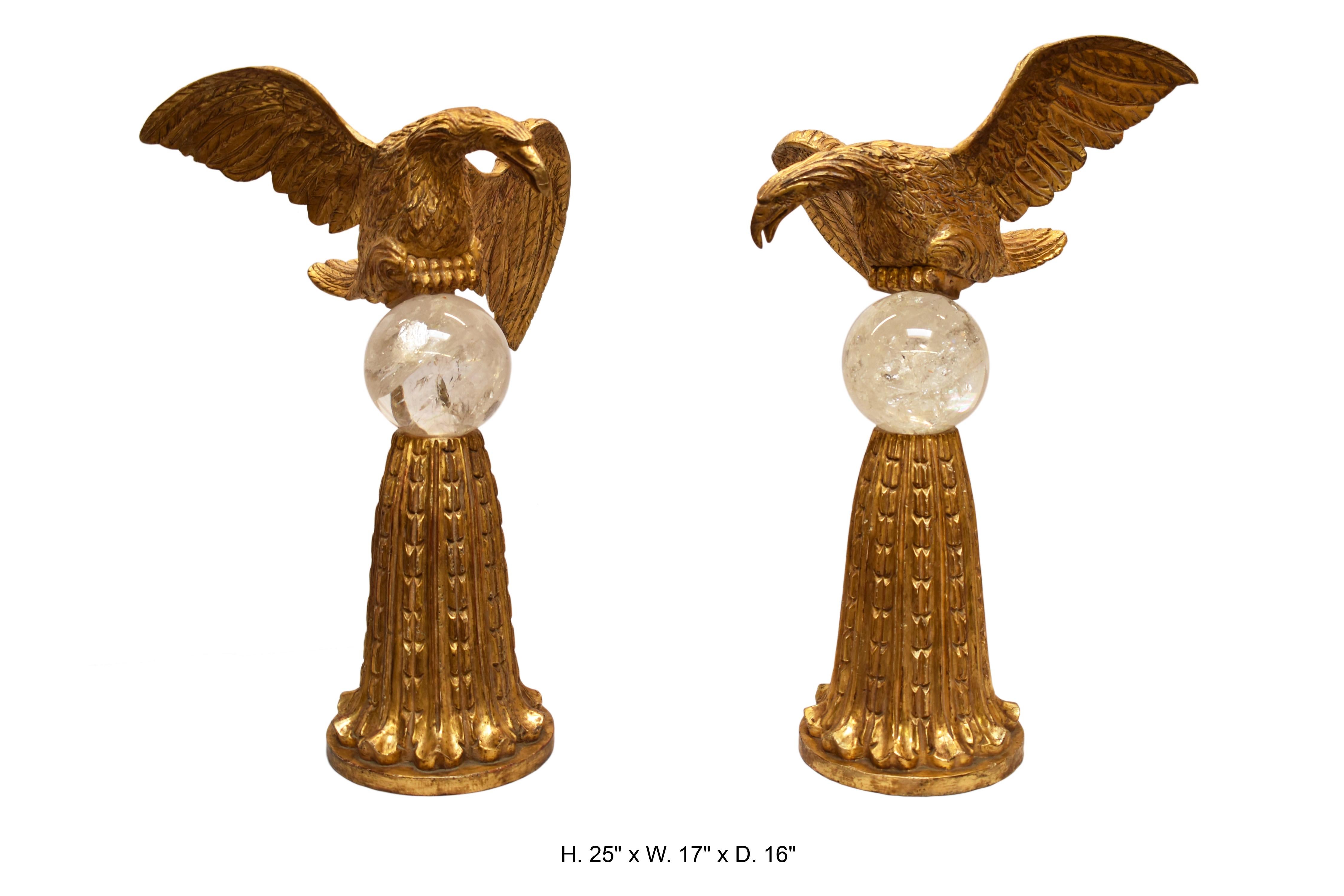 Paire opposée d'aigles en bois doré finement sculpté sur de grandes sphères en cristal de roche reposant sur des bases en bois doré finement sculpté avec motif d'acanthe.

Mesures : H 25