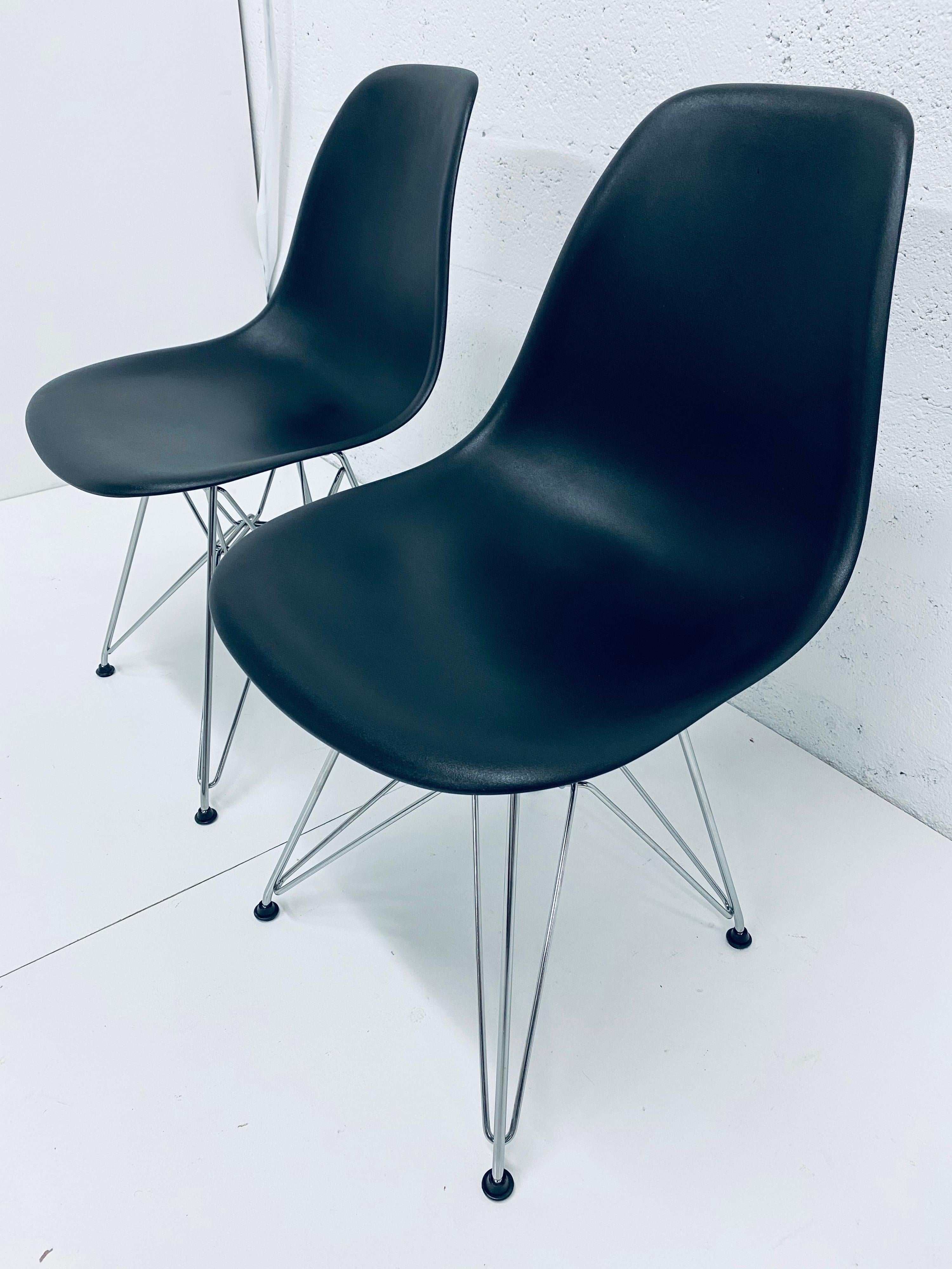 Two black moulded plastic side chairs with chrome Eiffel Tower bases by Charles and Ray Eames for Herman Miller, 2010s.

Charles and Ray Eames realized their dream to create a single-shell form over 80 years ago by making their molded chairs of