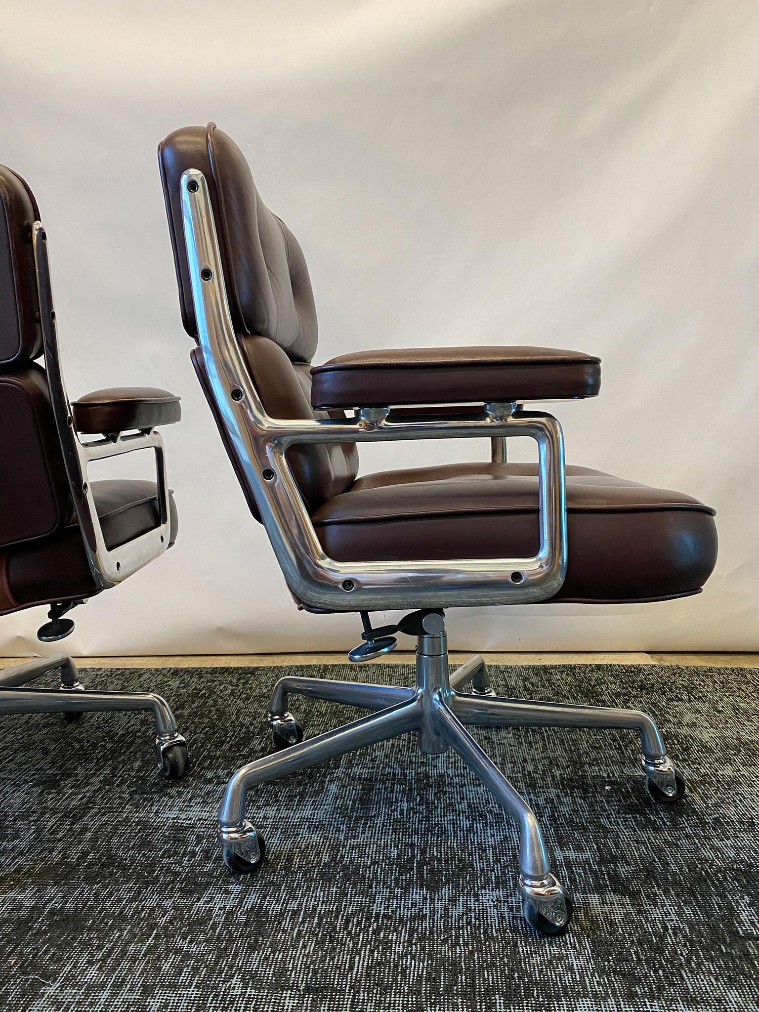 Beautiful pair of eggplant leather Time Life Executive chairs by Charles and Ray Eames for Herman Miller. Designed in 1959 for New York's Time Life building, they feature supple leather cushions and an aluminum frame. This pair tilt, swivel and