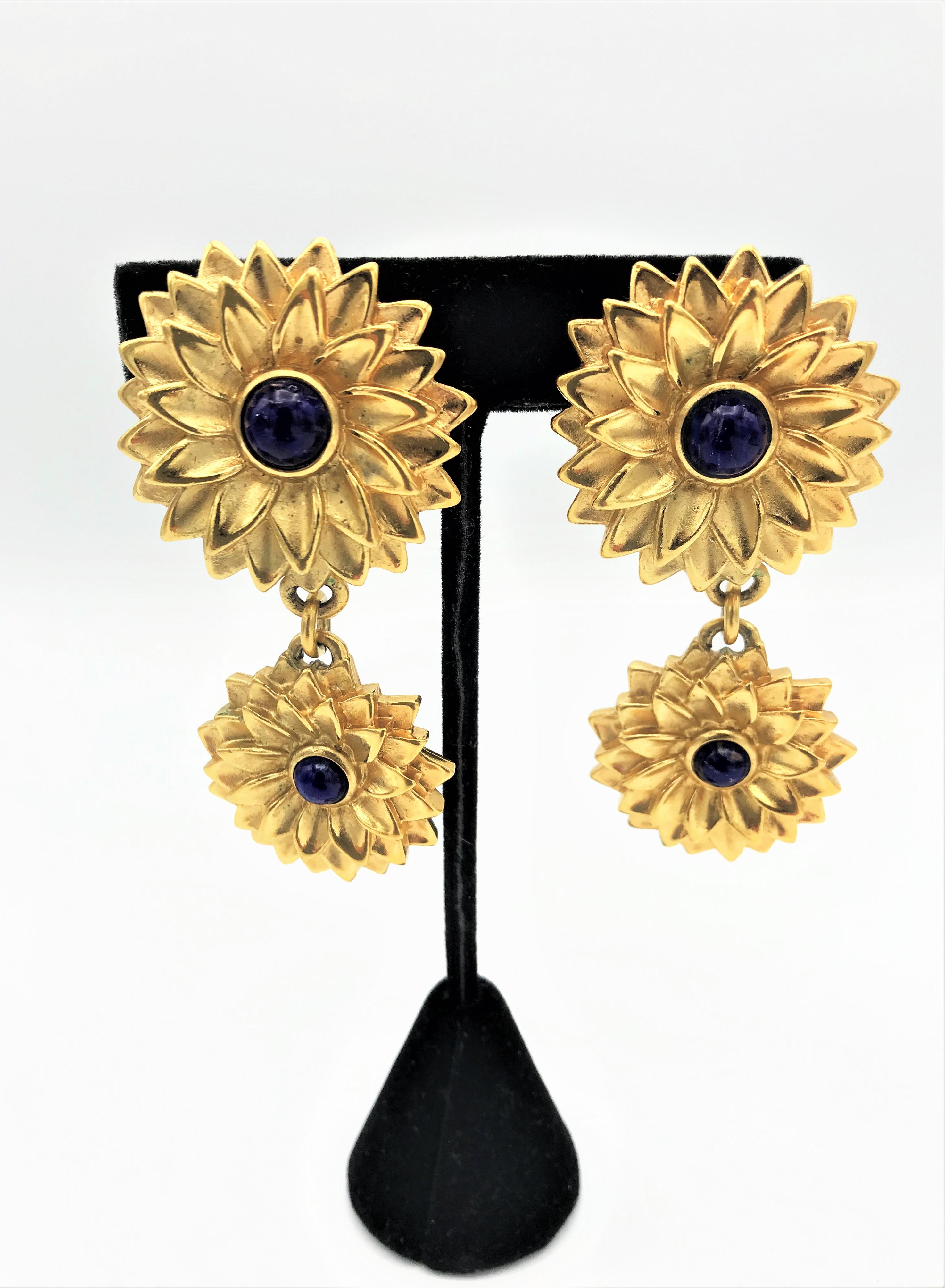A pair of ear clips from Lanvin/Germany consisting of 2 flowers hanging one below the other with a blue glas stone in the middle. The smaller flower hangs from the larger margaret flower above.
Measurement:
Height  7 cm 
The upper flower 3.5 cm 